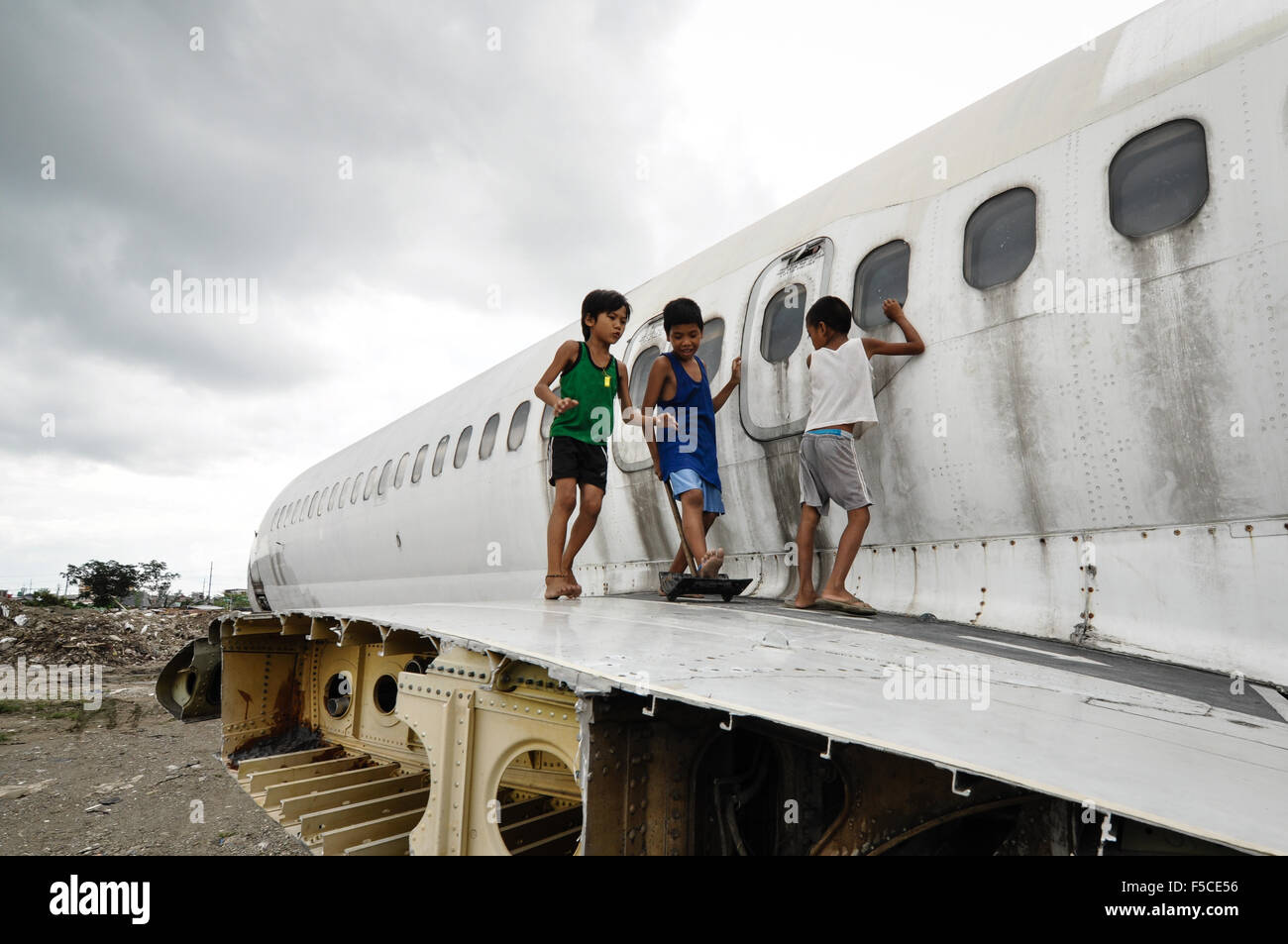 Kinder spielen auf dem Wrack des Flugzeugs auf ein unbebautes Grundstück in Paranaque City, südlich von Manila, Philippinen. Stockfoto