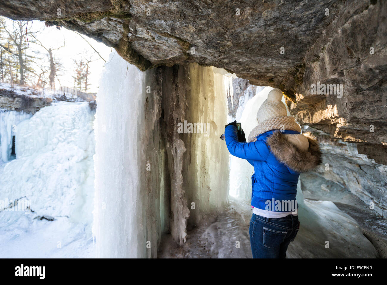 Kaukasischen Frau in Winterkleidung nimmt ein Bild auf die gefrorenen Minnehaha Fälle im Winter, Minneapolis, MN, USA Stockfoto
