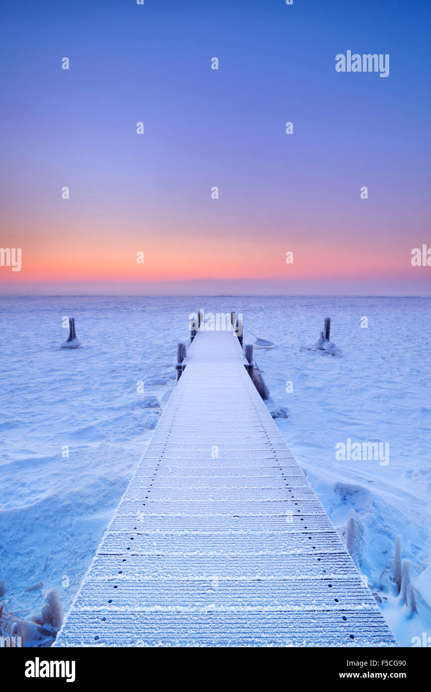 Steg auf einem zugefrorenen See. Fotografiert bei Sonnenaufgang an einem rekordverdächtigen kalten Morgen in den Niederlanden. Stockfoto