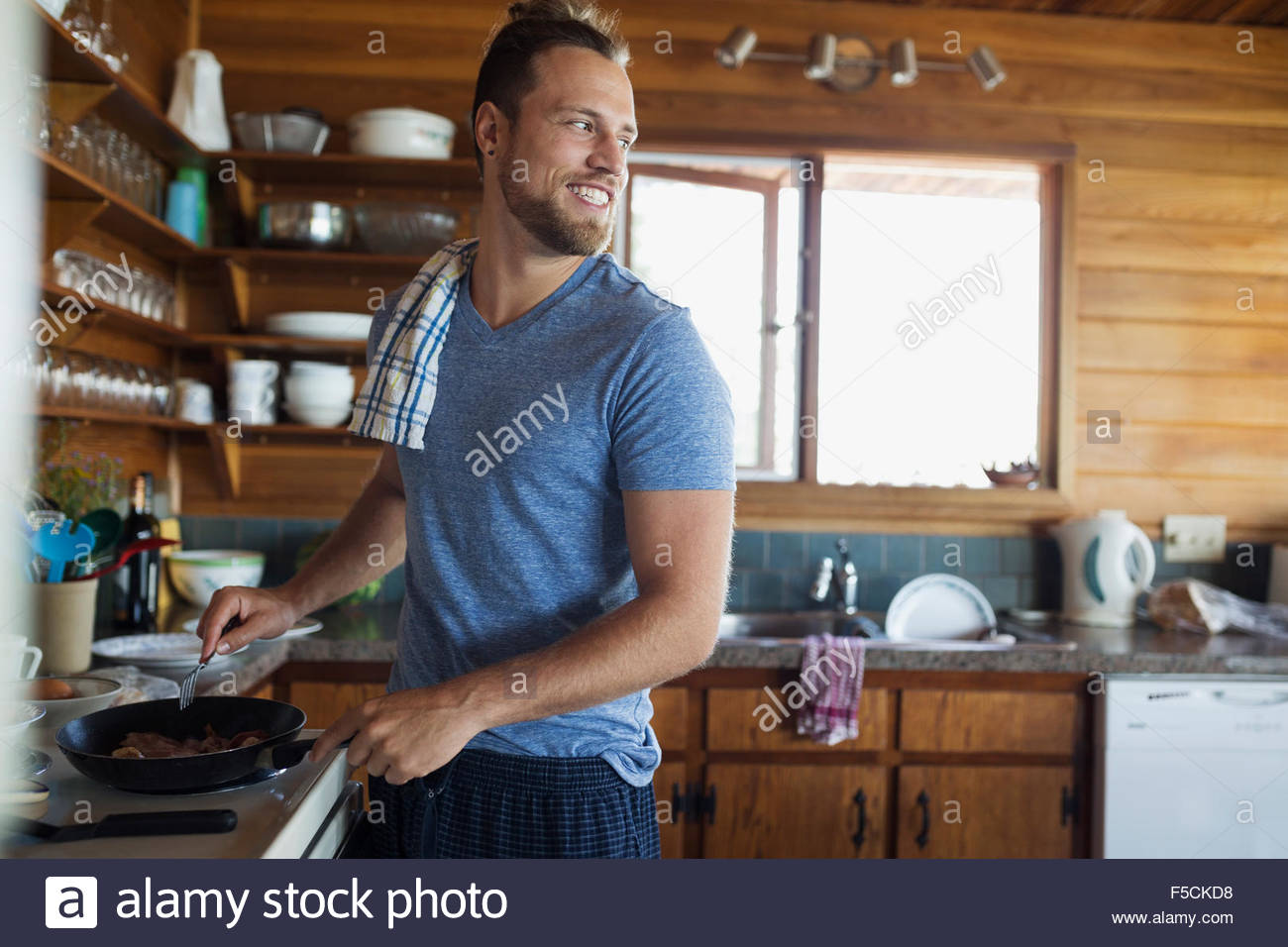 Junger Mann Kochen Frühstück in Kabine Küche Stockfoto