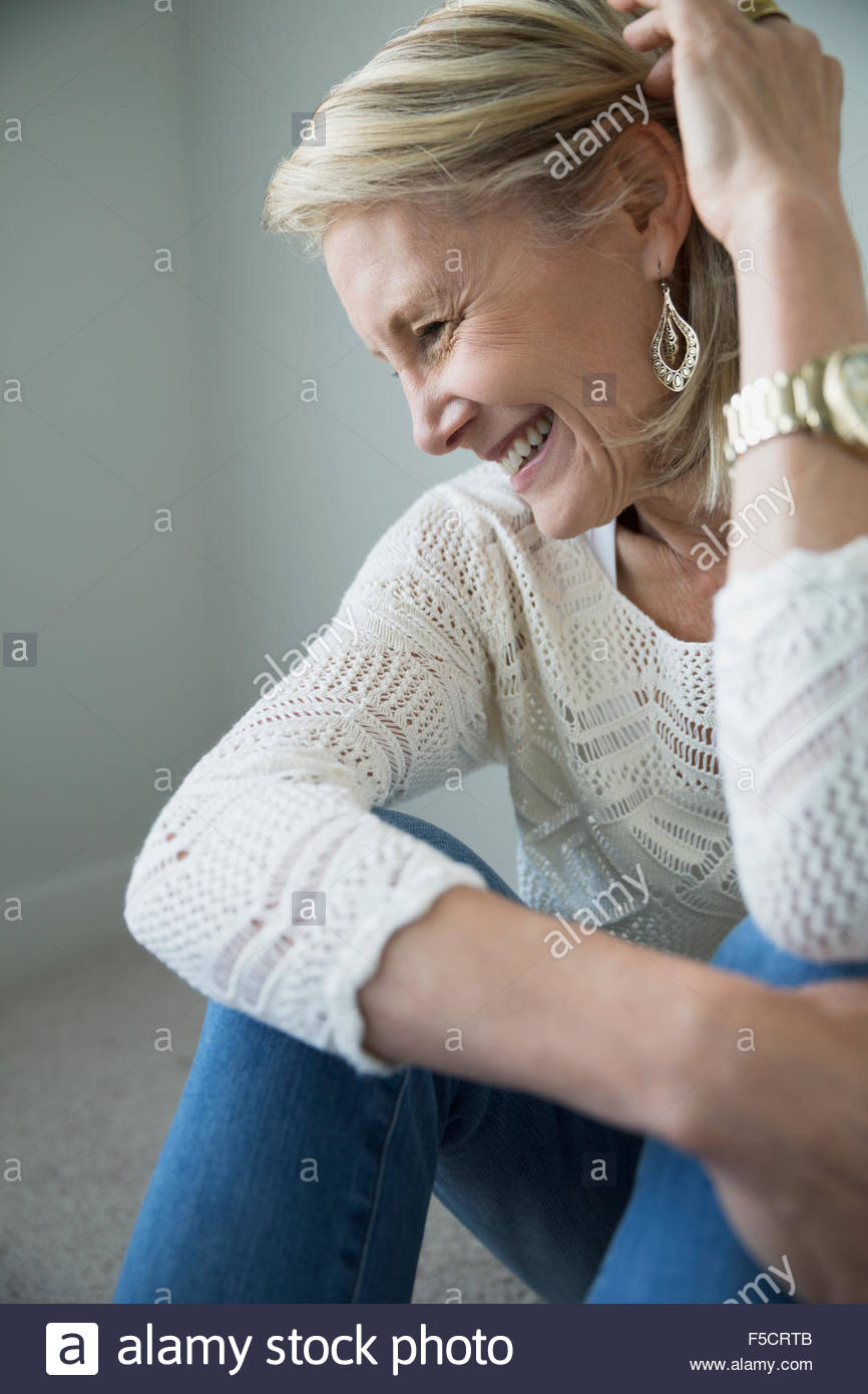 Ältere Frau umarmt Knie lachen Stockfoto