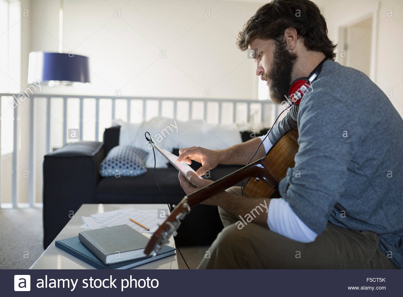 Mann mit Gitarre Musikaufnahmen mit digital-Tablette Stockfoto