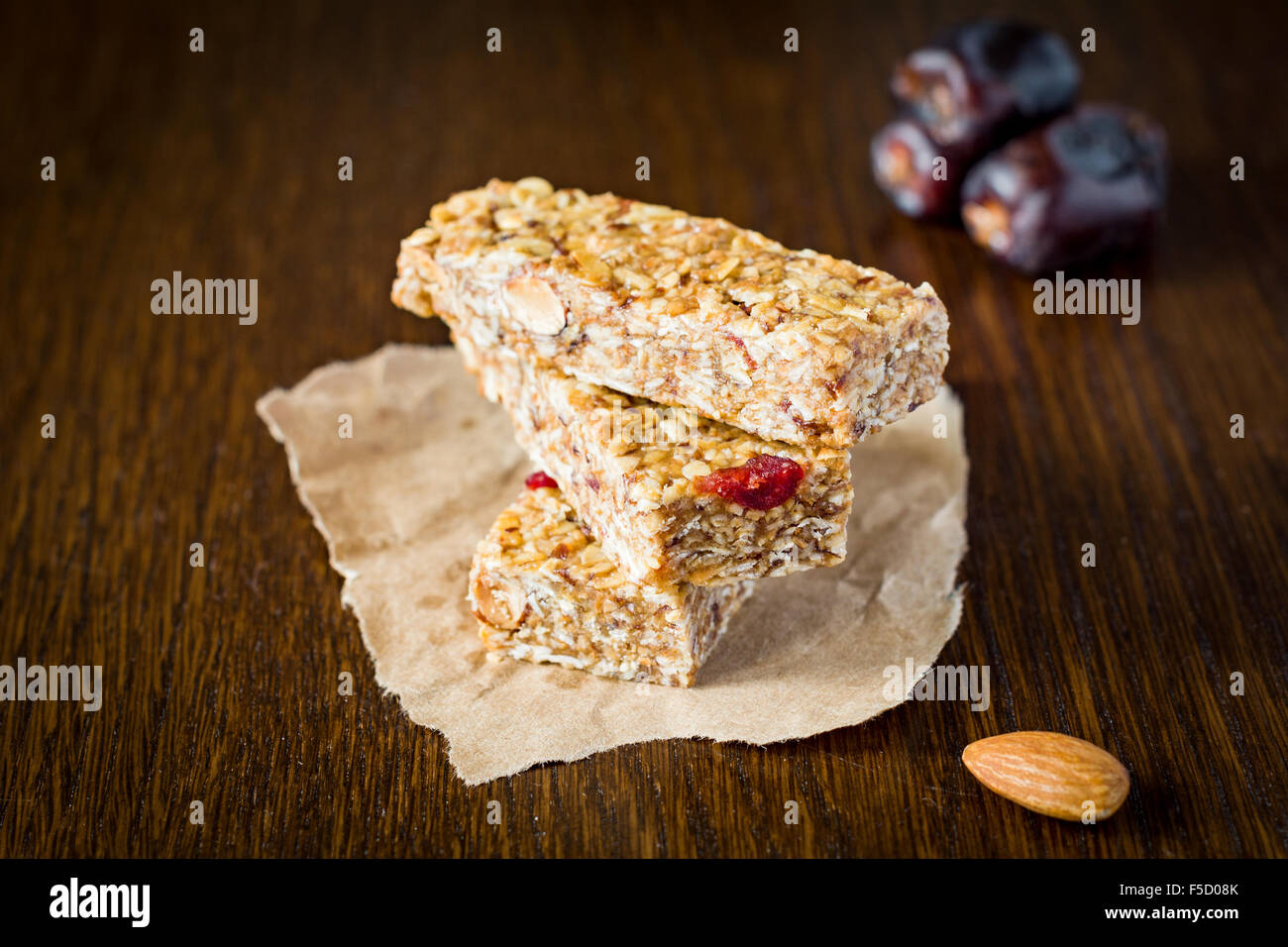 Müsliriegel oder Energieriegel mit Hafer, Datteln und Nüssen auf braunem Hintergrund aus Holz. Gesunder Snack für Yoga, Fitness oder Power Lifter Stockfoto