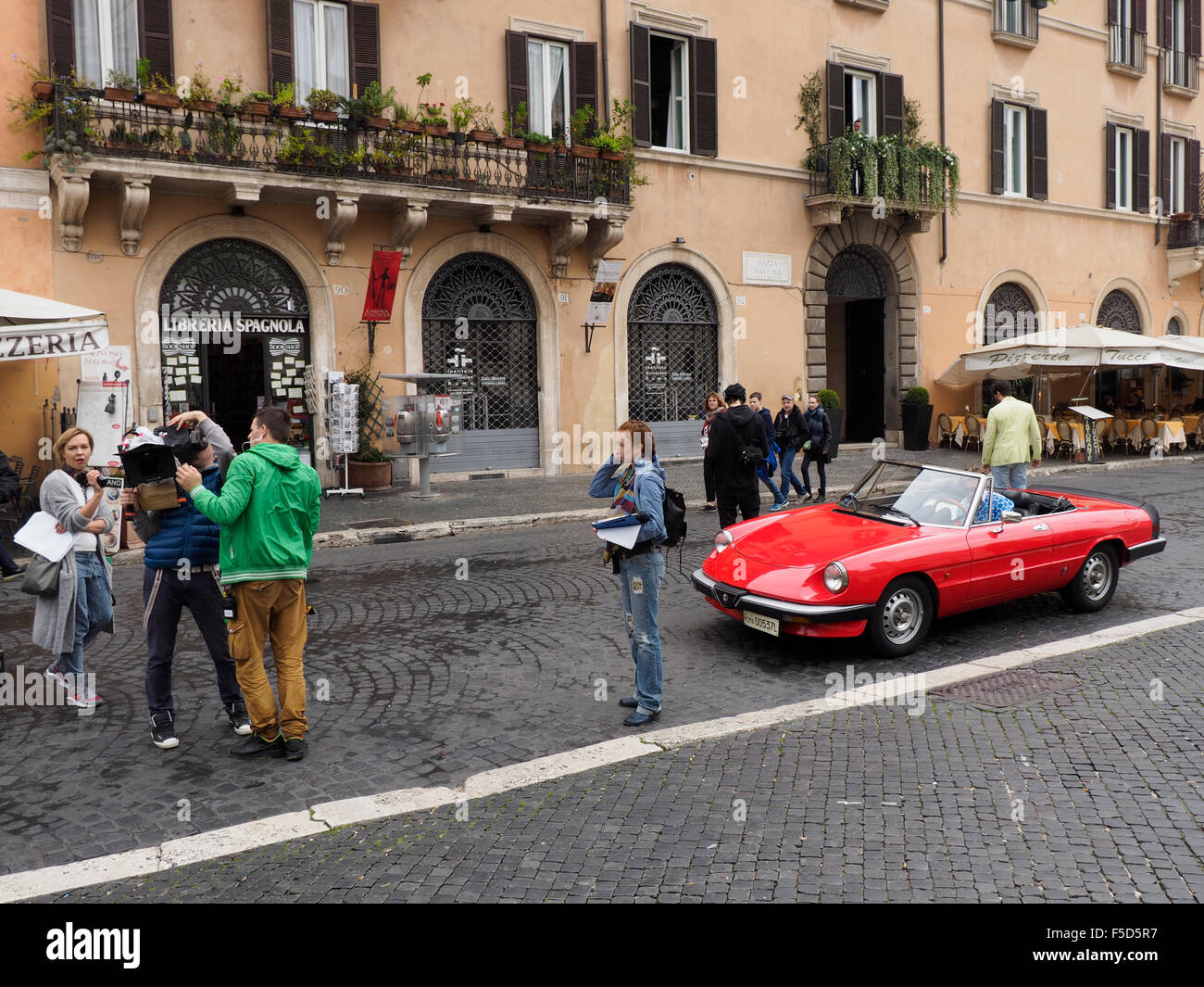 Filmteam und männliche Models in einer klassischen Alfa Romeo Sportwagen auf der Piazza Navona in Rom, Italien Stockfoto