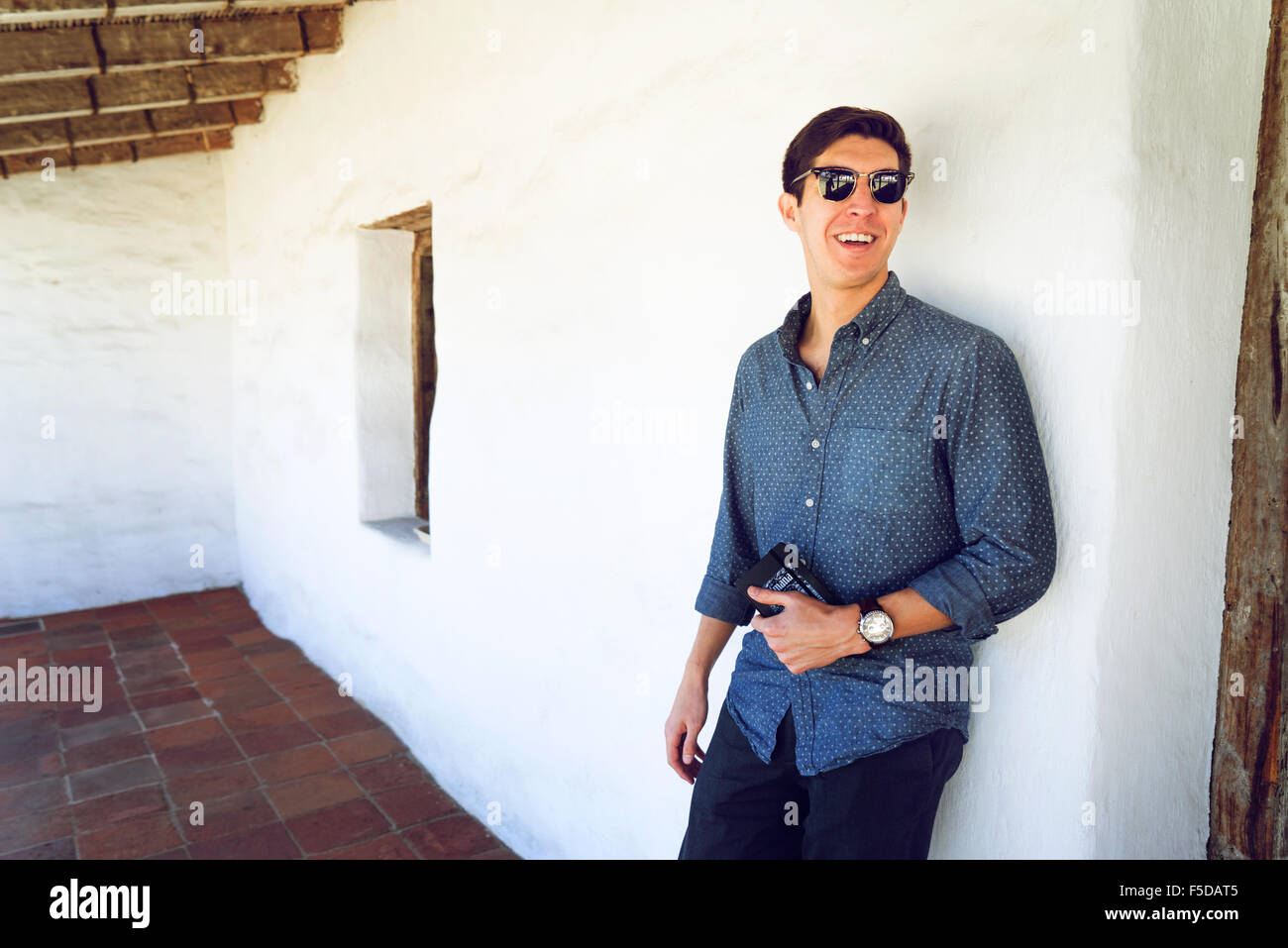 Ein junger lässige Geschäftsmann lächelnd eine Wand gelehnt Stockfoto