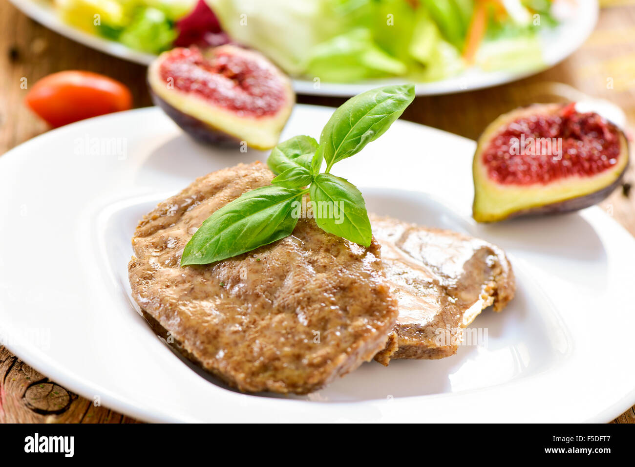 Nahaufnahme von einigen Veggie Cordon Bleu in einen Teller und einen Teller mit Salat im Hintergrund Stockfoto