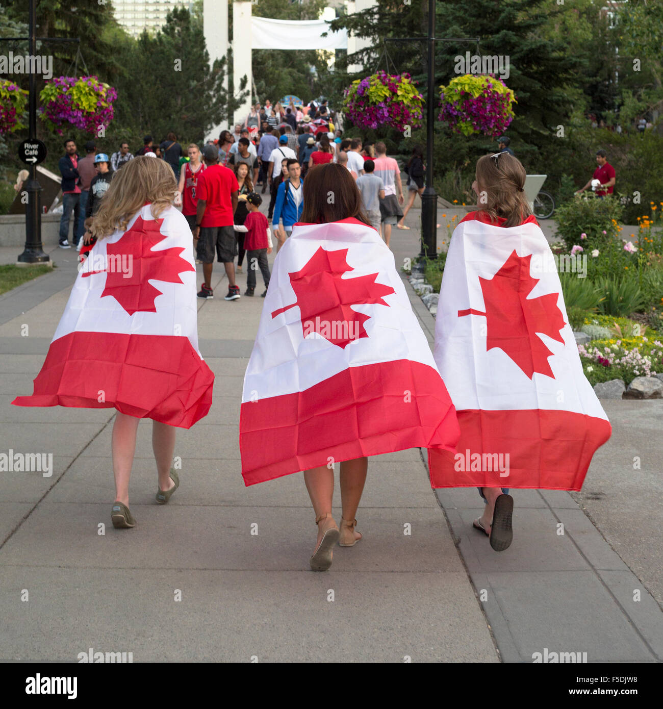 Drei junge Frauen tragen am 1. Juli, dem Canada Day, im Prince's Island Park, Calgary, Alberta, kanadische Flaggen Stockfoto