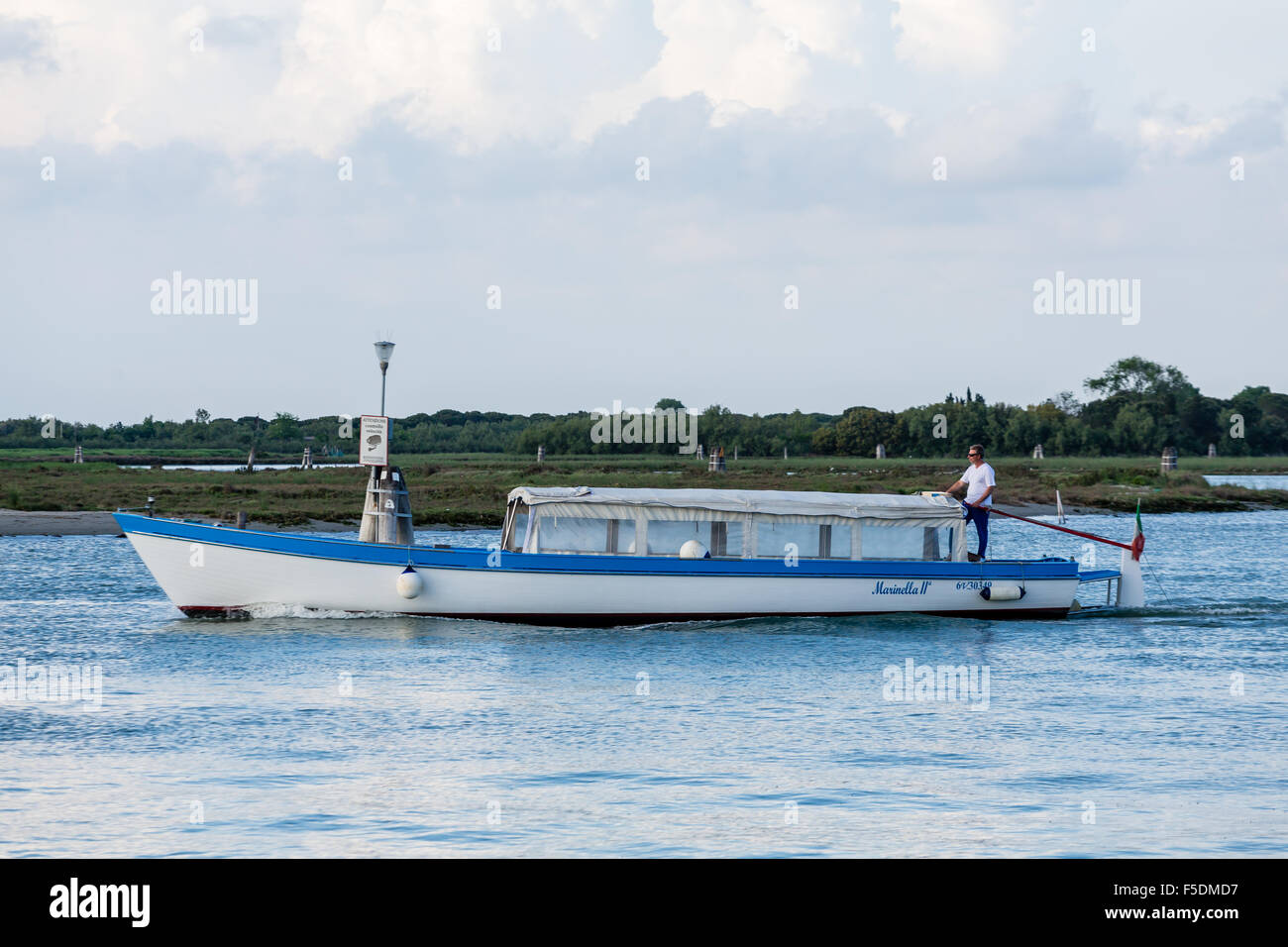 Ein Mann, ein Boot durch einen Kanal von Venedig mit einer altmodischen Ruder Lenkung Stockfoto