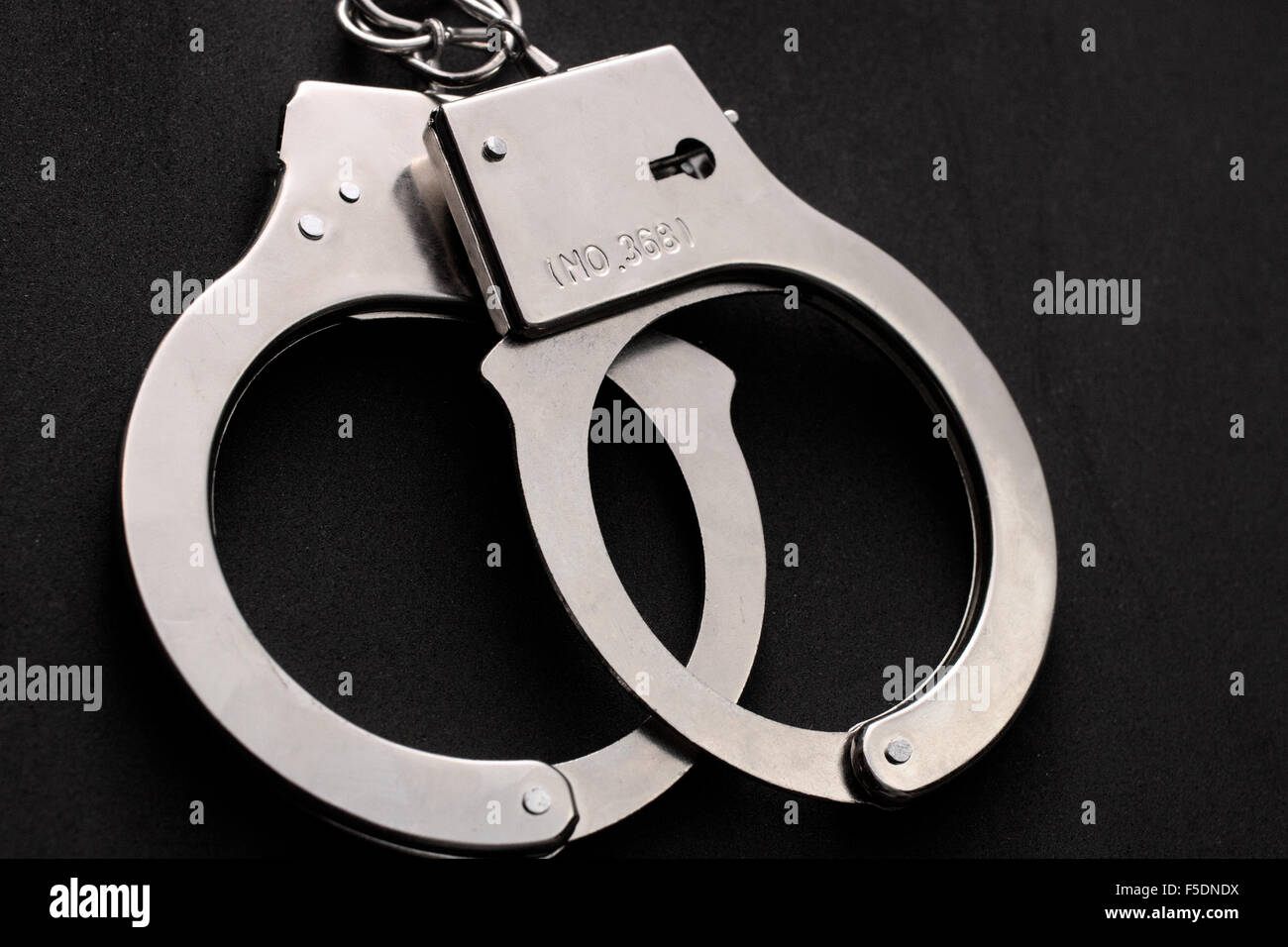 Handschellen auf schwarzem Hintergrund Stockfoto