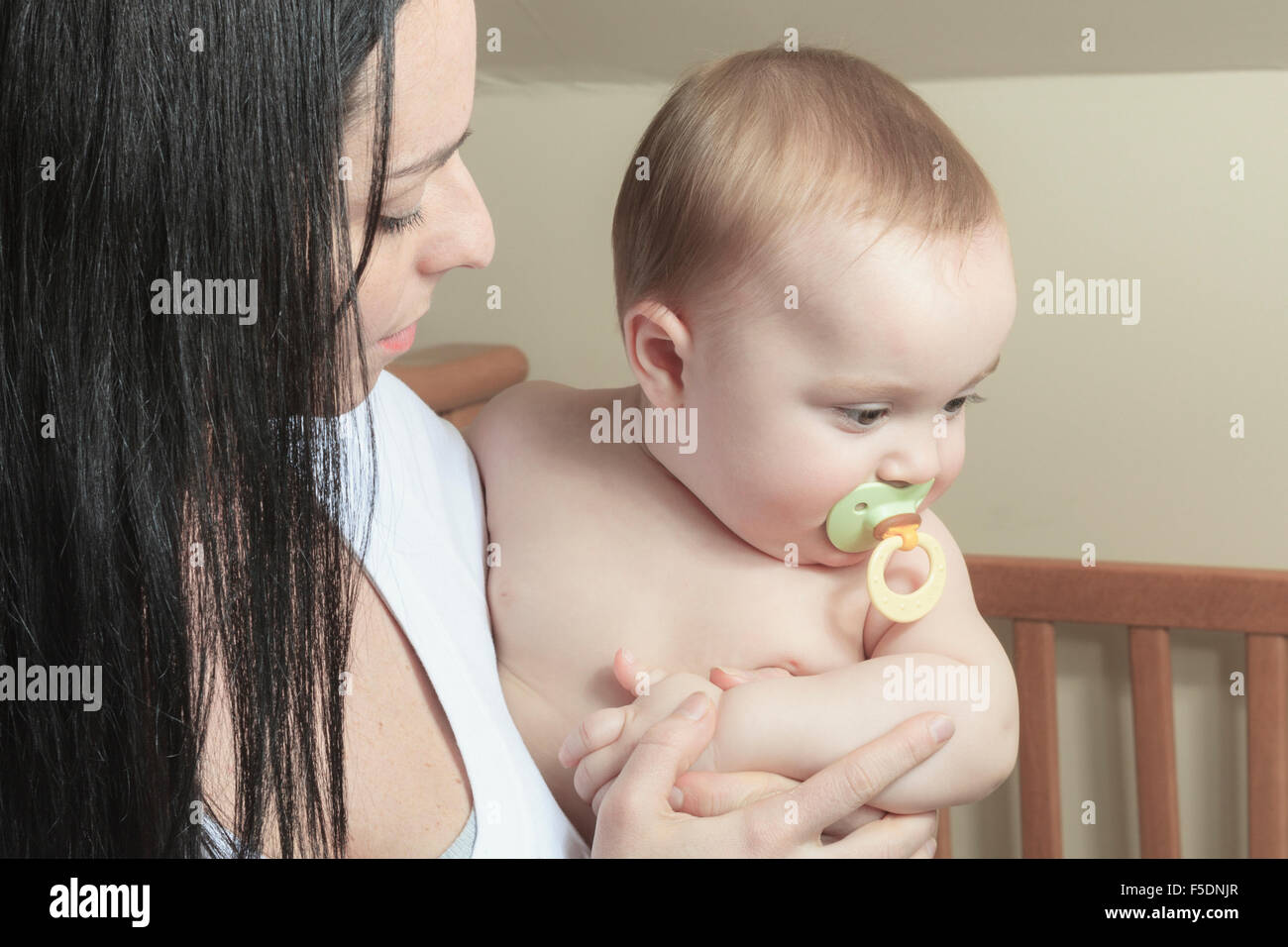 Hingebungsvolle Mutter Sohn Festlegung in Krippe für Nickerchen im Schlafzimmer Stockfoto
