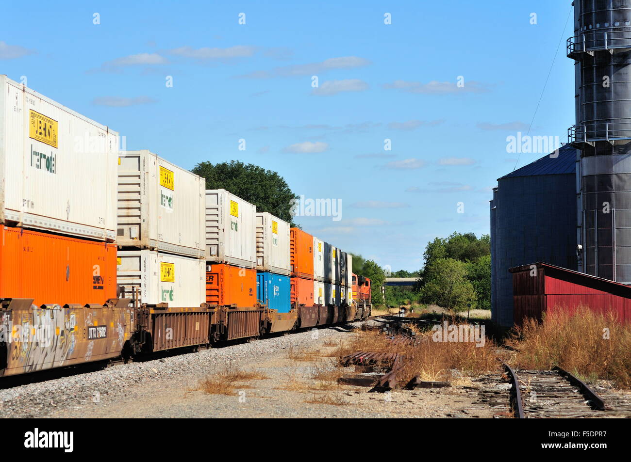 Zwei Lokomotiven führen ein Burlington Northern Santa Fe Güterzug Vergangenheit ein Landwirt kooperative und durch Verwalter, Illinois, USA. Stockfoto