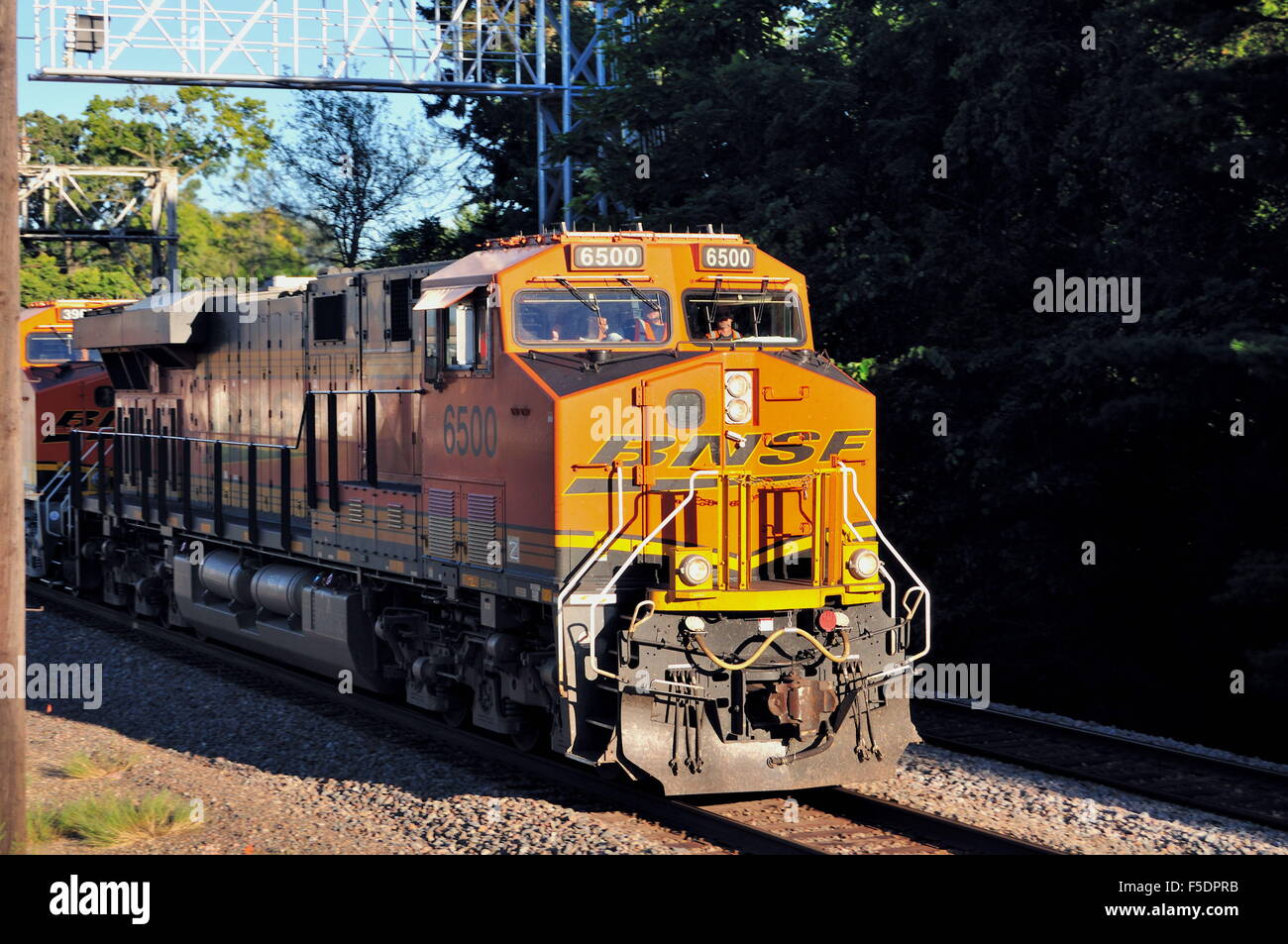 Ein Burlington Northern Santa Fe Güterzug Auffangen von Schatten und ein Signal tower Poltern durch Rochelle, Illinois, USA. Stockfoto