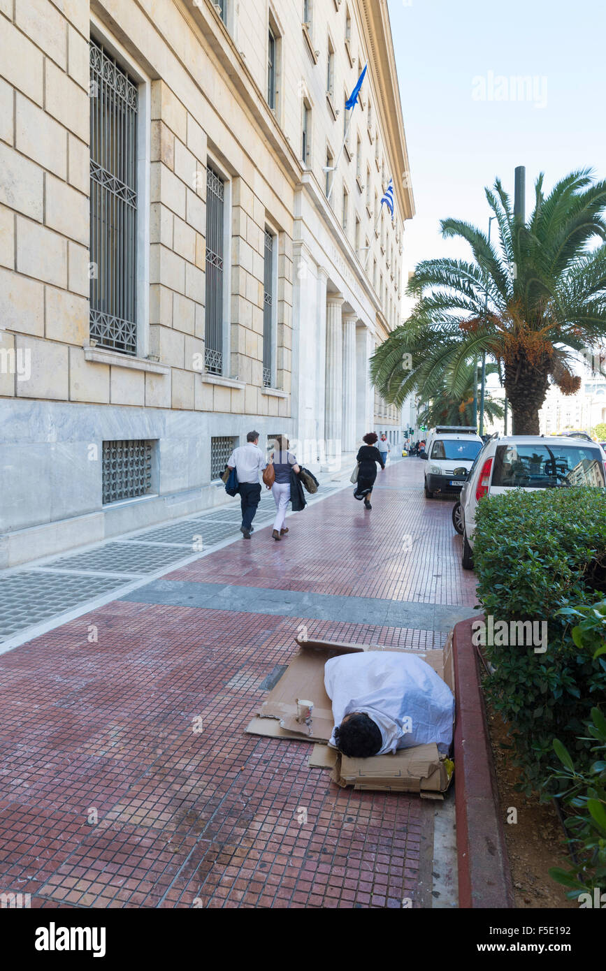 Athen, Griechenland - 27. Oktober 2015: Ein Bettler schläft auf dem Boden vor der Zentralbank von Griechenland Stockfoto