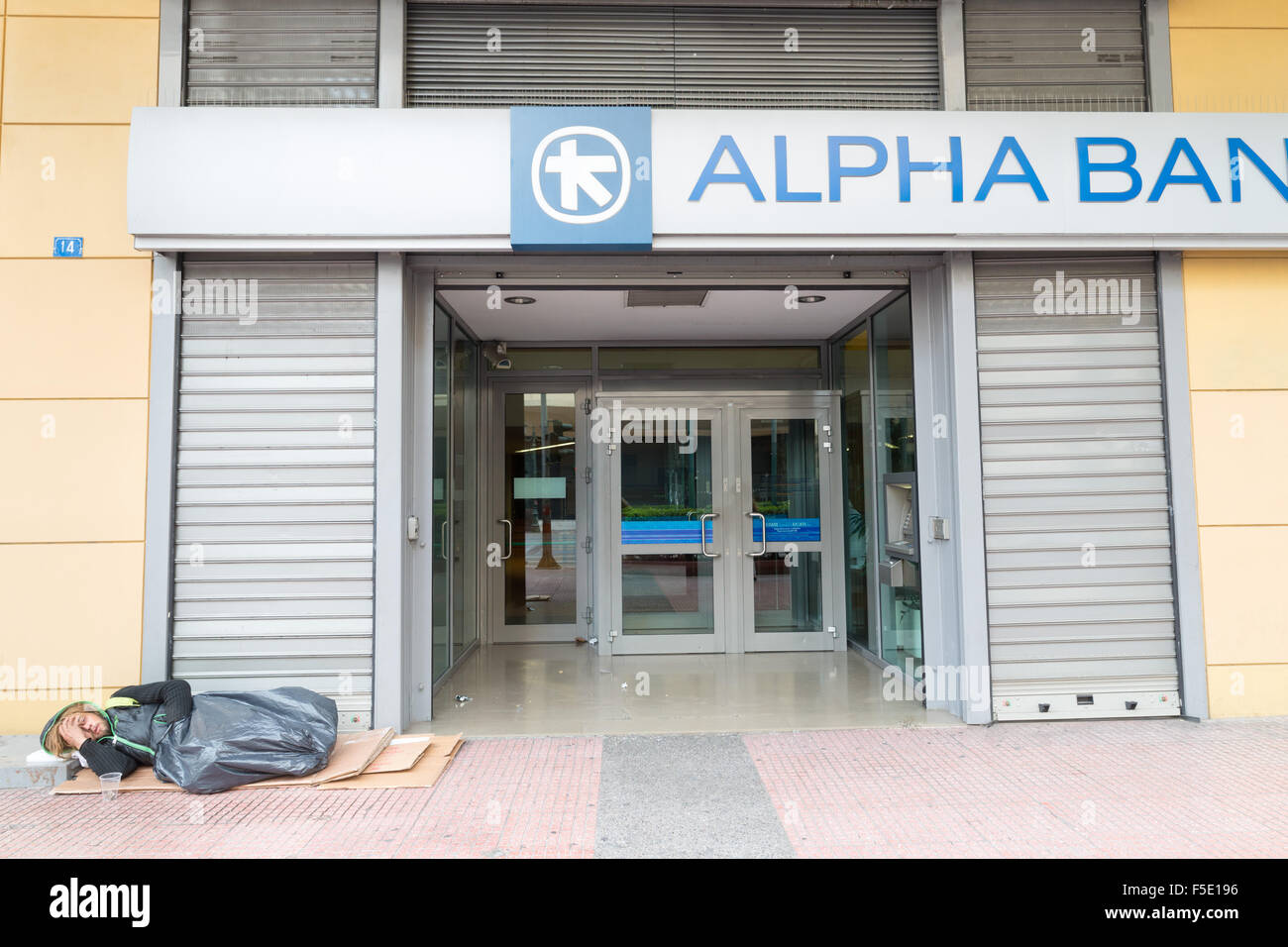 Athen, Griechenland - 31. Oktober 2015: Bettler an der Tür einer Bank eingeschlafen Stockfoto