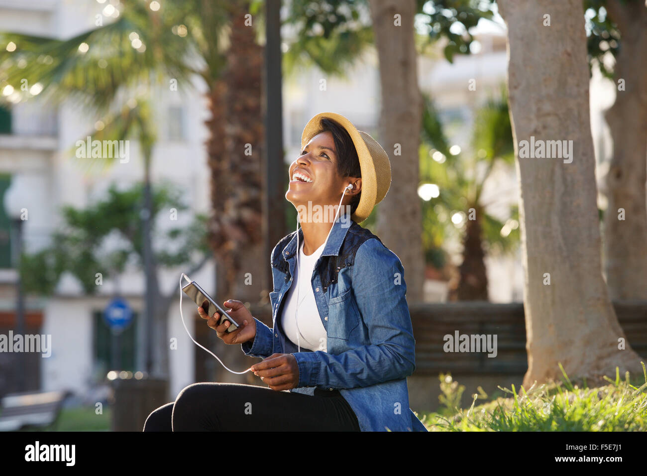 Porträt einer lächelnden jungen afroamerikanischen Frau anhören von Musik auf Handy Stockfoto