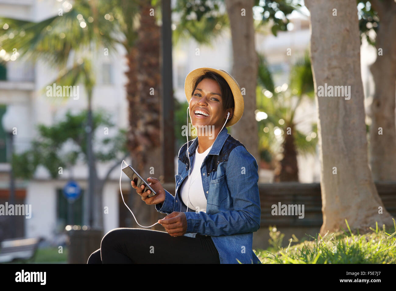 Porträt einer jungen schwarzen Frau lachend mit Handy Stockfoto