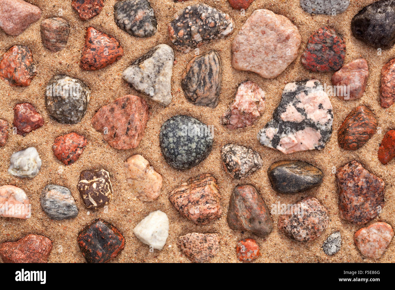 nassen bunten Steinen auf Sand als Hintergrund angeordnet Stockfoto