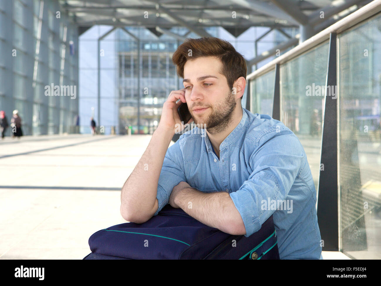 Porträt von ein hübscher junger Mann am Boden für den nächsten Flug warten und telefonieren mit Handy Stockfoto