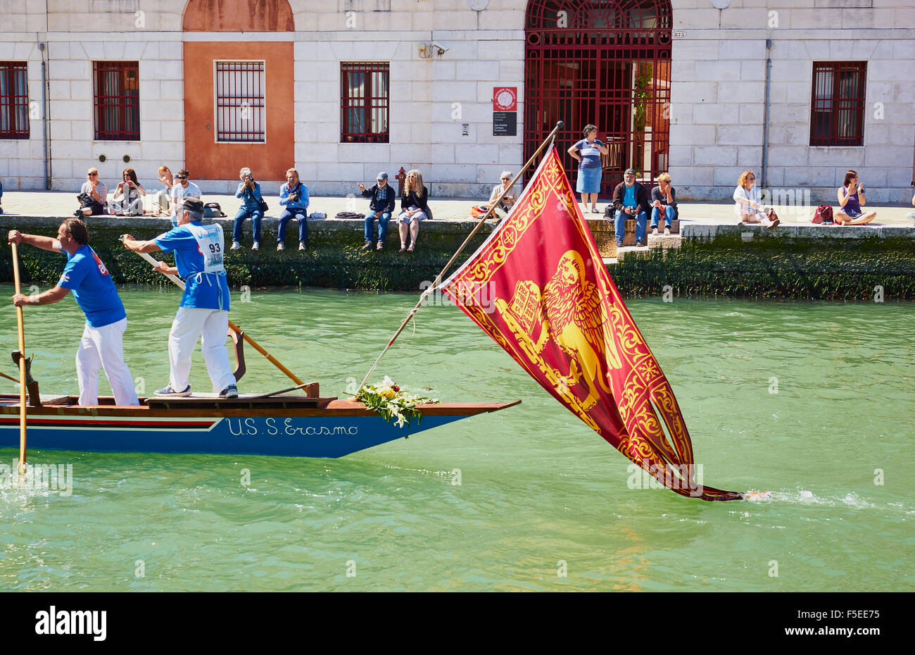 Ein Team, die Teilnahme an der Vogalonga, mit dem Boot unter der venezianischen Flagge eines geflügelten Löwen Venedig Veneto Italien Europa Stockfoto