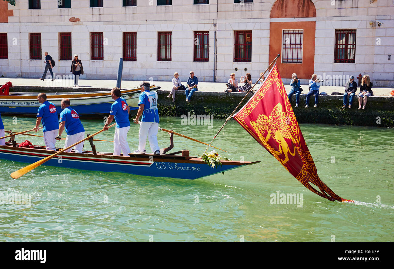 Ein Team, die Teilnahme an der Vogalonga, mit dem Boot unter der venezianischen Flagge eines geflügelten Löwen Venedig Veneto Italien Europa Stockfoto