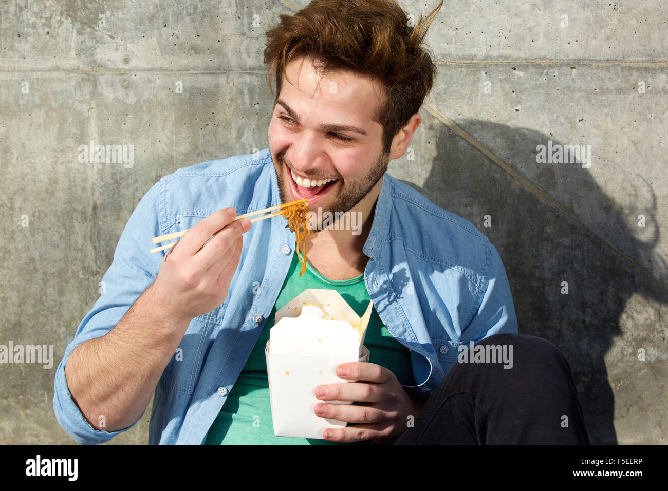 Porträt von ein glücklicher Mann Essen Essen mit Stäbchen Stockfoto