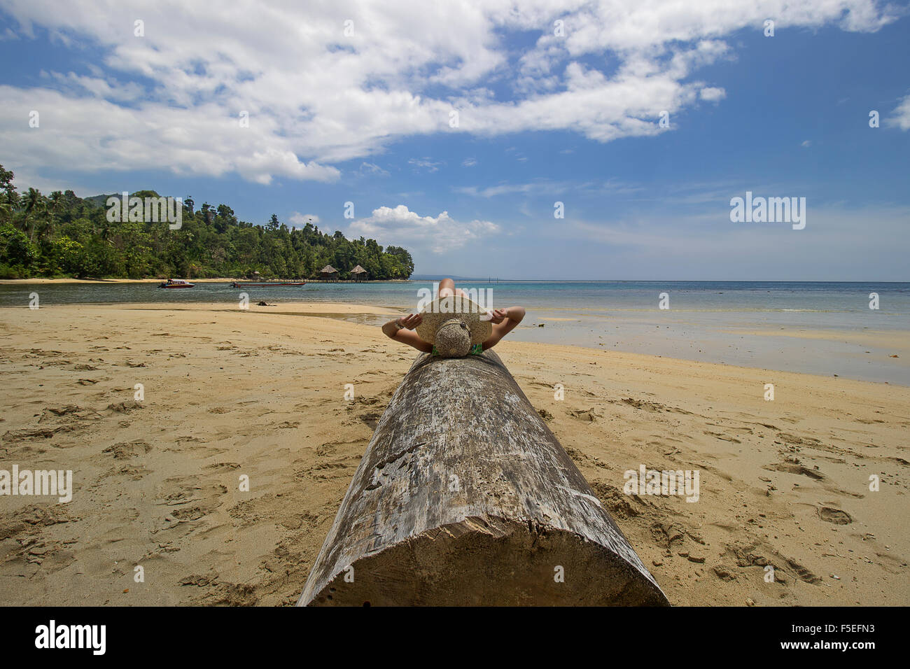 Frau liegend auf einem Baumstamm auf den Strand, Seram, Molukken, Indonesien Stockfoto
