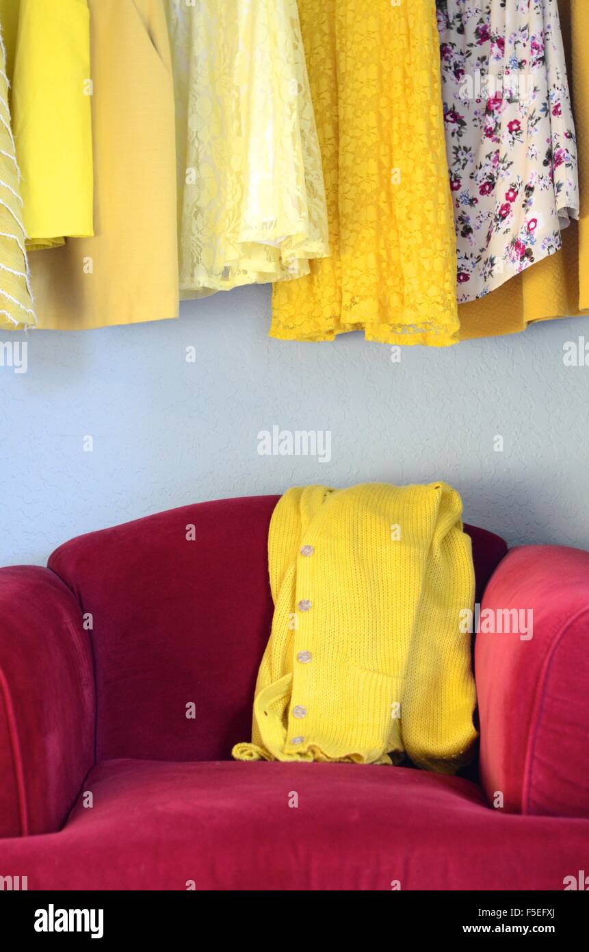 Gelbe Kleider und gelbe Strickjacke auf einem rotem samt Stuhl Stockfoto