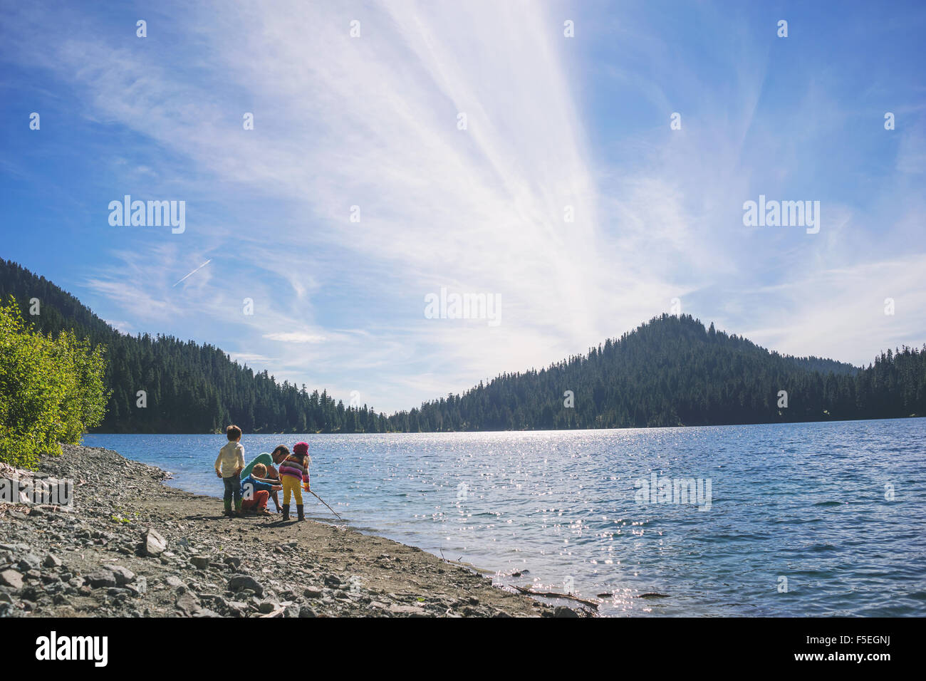 Mann mit drei Kindern spielen an einem See Stockfoto