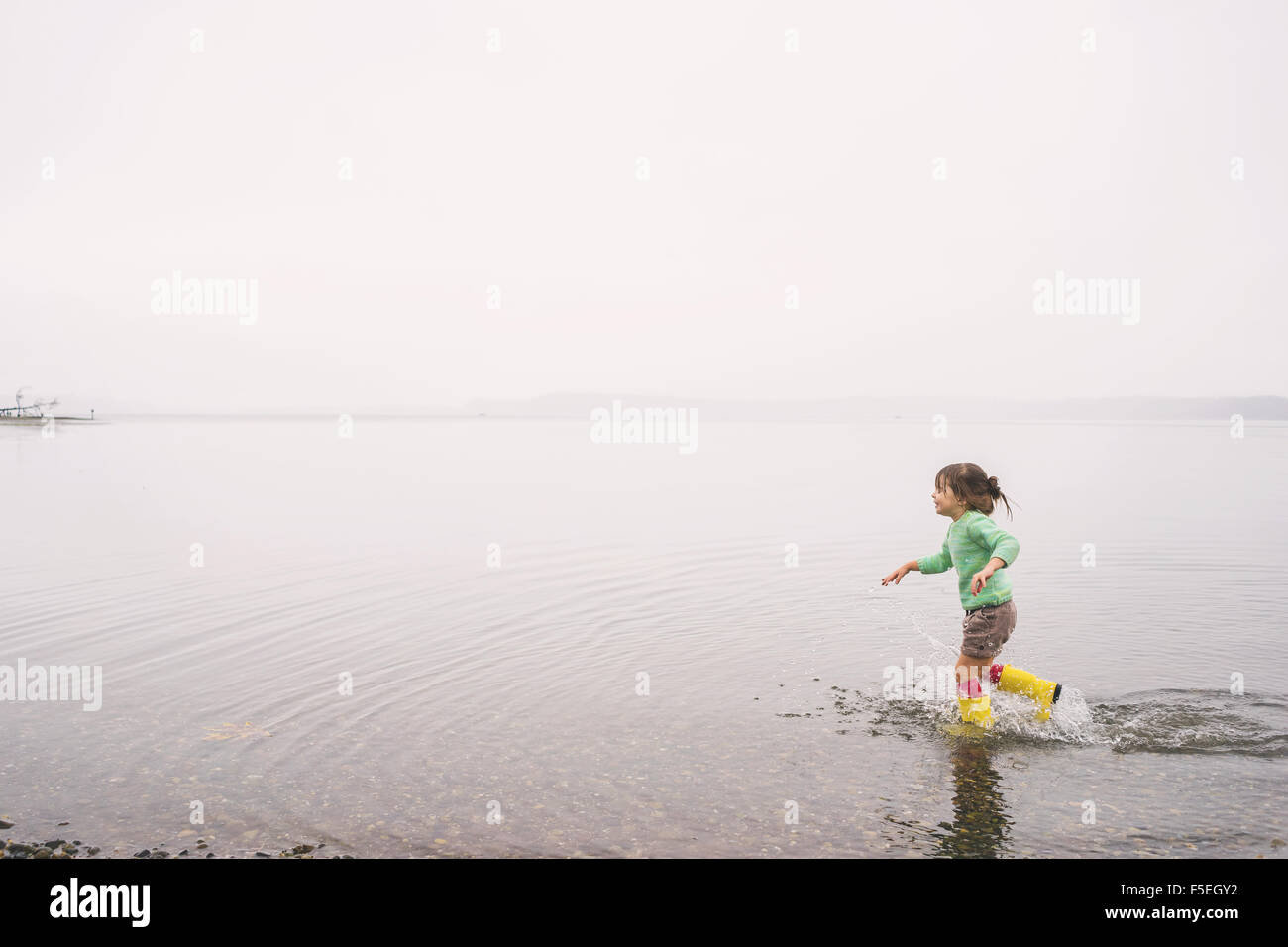 Mädchen läuft in einem See mit gummistiefeln Stockfoto