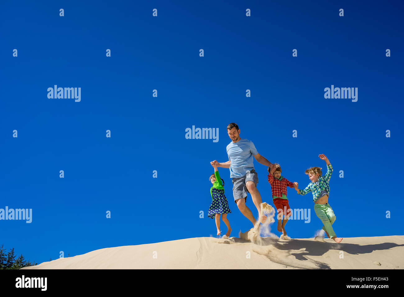 Vater und drei Kinder liefen eine Sanddüne Stockfoto