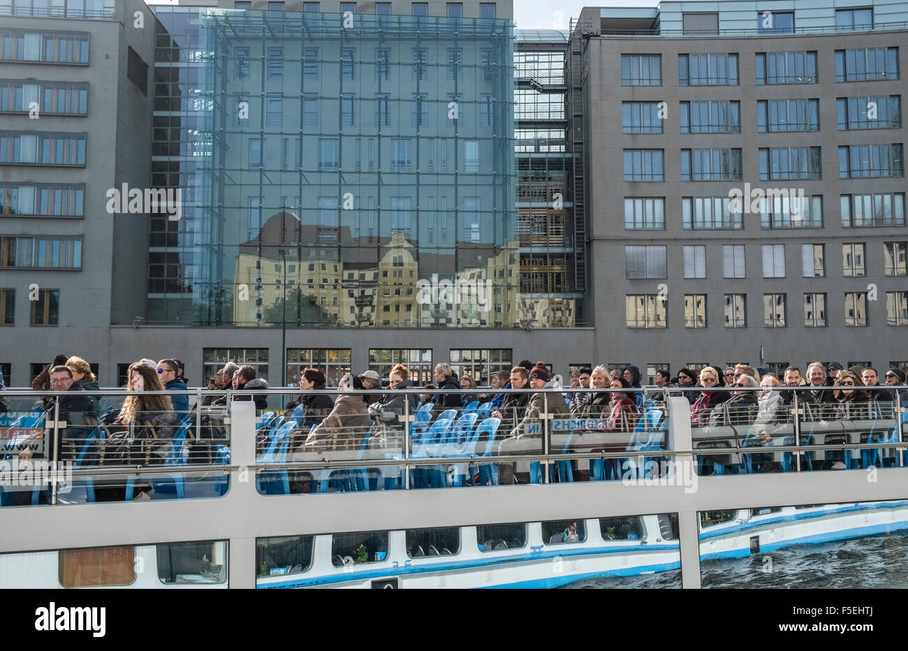 Touristen, die auf Bootsfahrt auf der Spree mit Nikolaiviertel Quartal spiegelt sich im Fenster gegenüber, Berlin, Deutschland Stockfoto