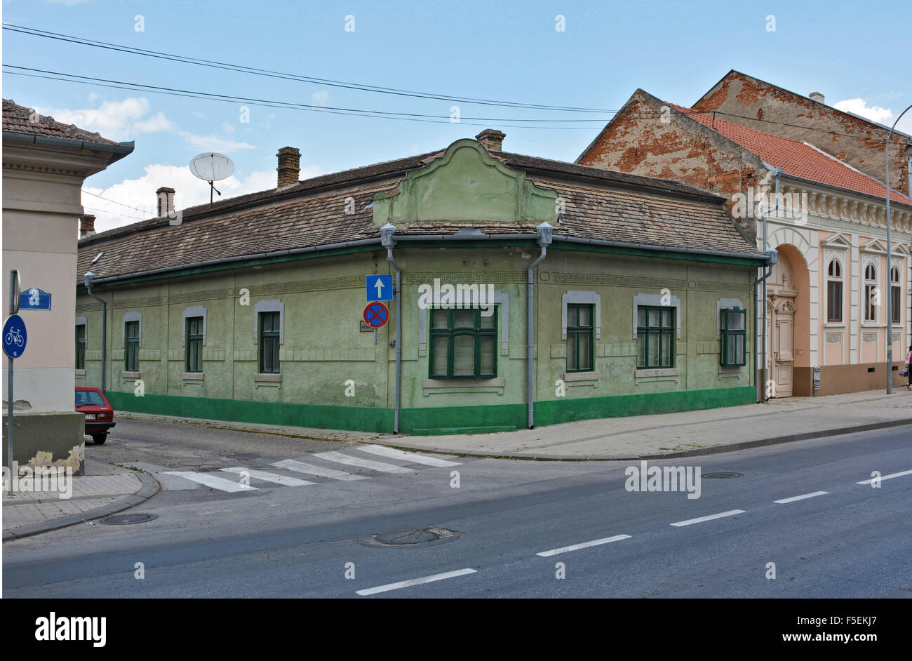 Schöne, niedrige Altstadthaus an der Ecke zweier Straßen mit einer Satellitenschüssel auf dem Dach. Stockfoto