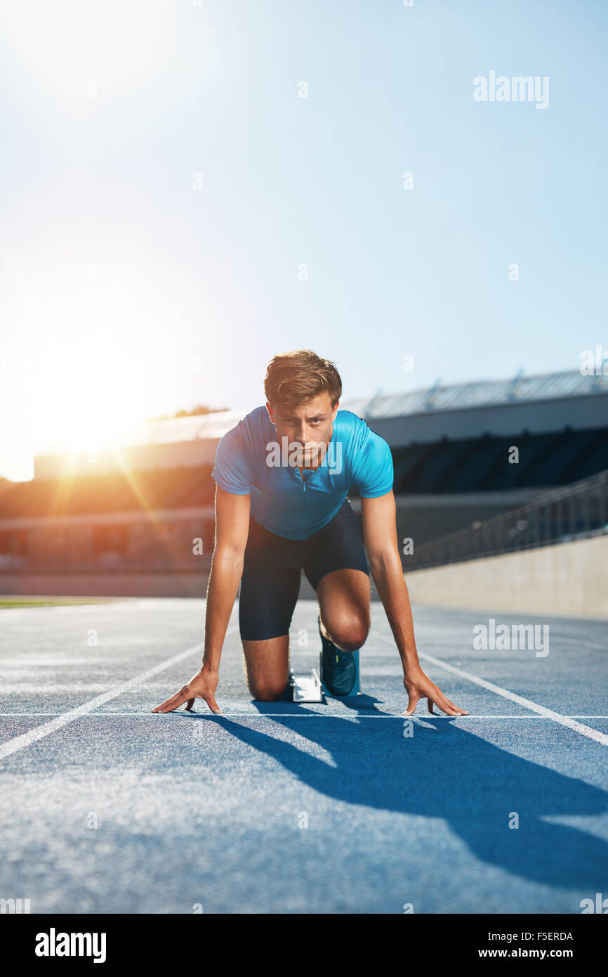 Vertikale Aufnahme des jungen männlichen Läufer unter Lage mit Blick auf die Kamera startbereit. Sprinten mit Entschlossenheit. Athleten in St. Stockfoto