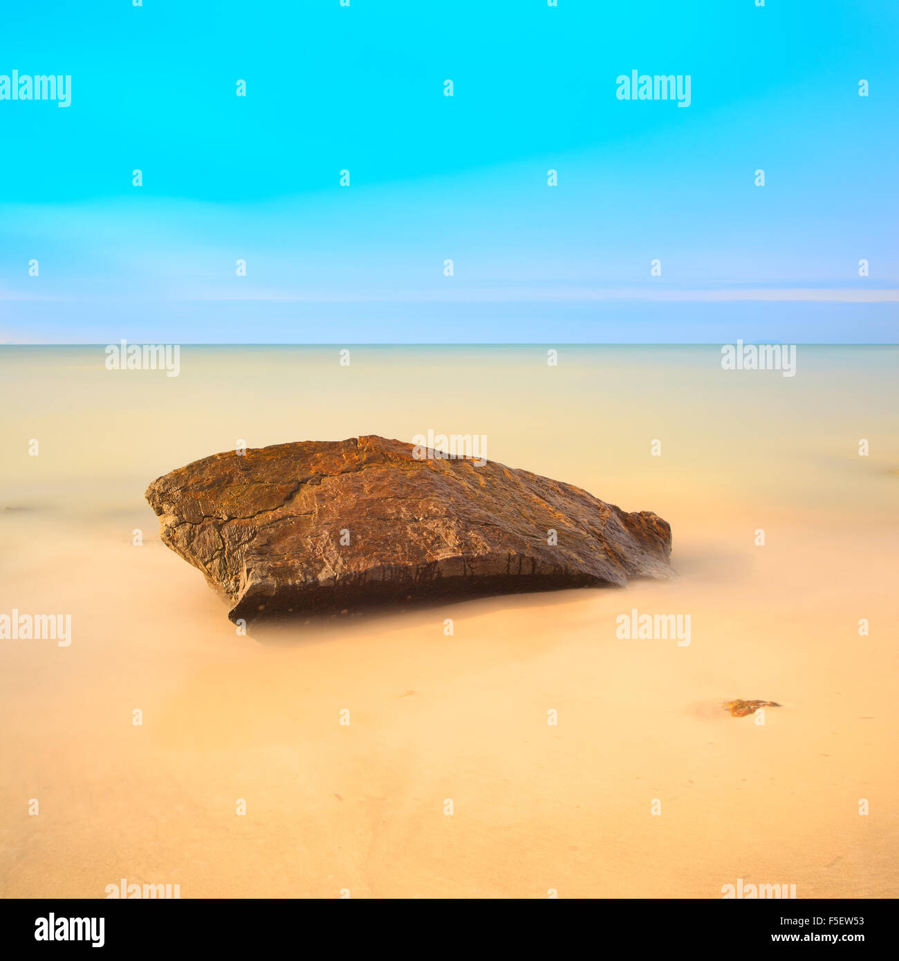 Einem flachen Felsen an einem goldenen Strand. Langzeitbelichtung Fotografie. Stockfoto