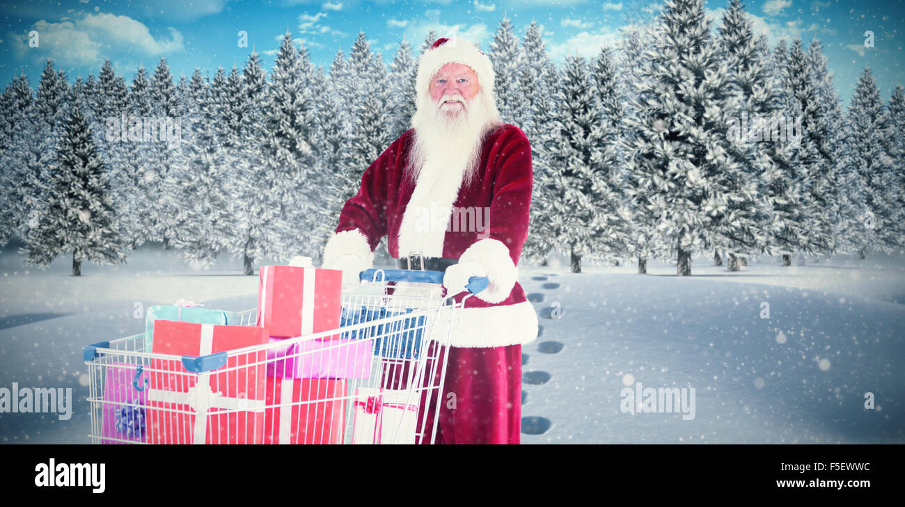 Zusammengesetztes Bild von Santa schiebt einen Einkaufswagen mit Geschenken Stockfoto