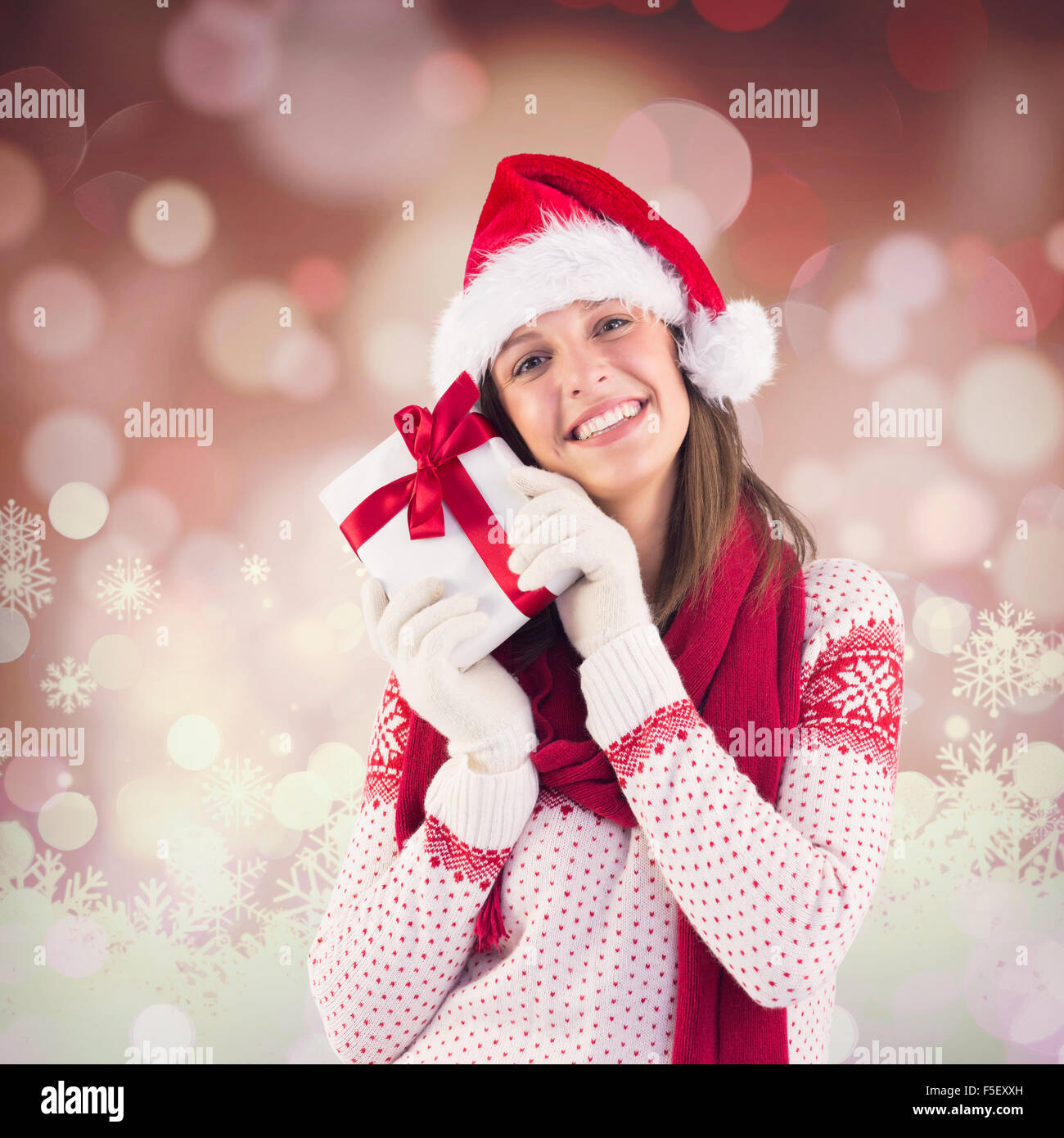 Zusammengesetztes Bild attraktive Frau trägt Weihnachtsmütze mit Geschenk Stockfoto