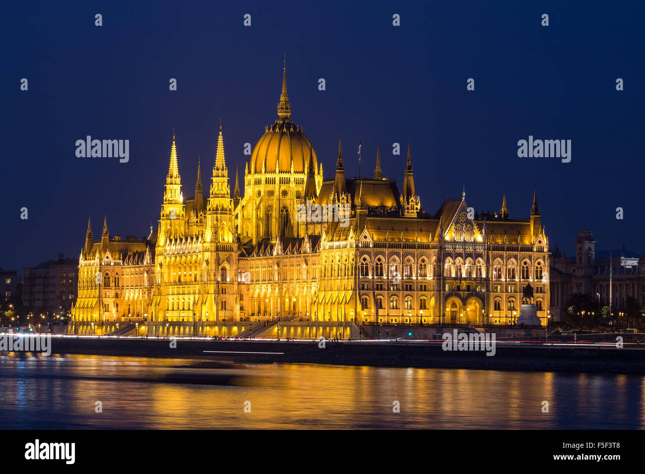 Eine Seitenansicht des ungarischen Parlamentsgebäudes entlang der Donau in der Nacht mit dem Bau beleuchtet und Reflexionen in der Stockfoto