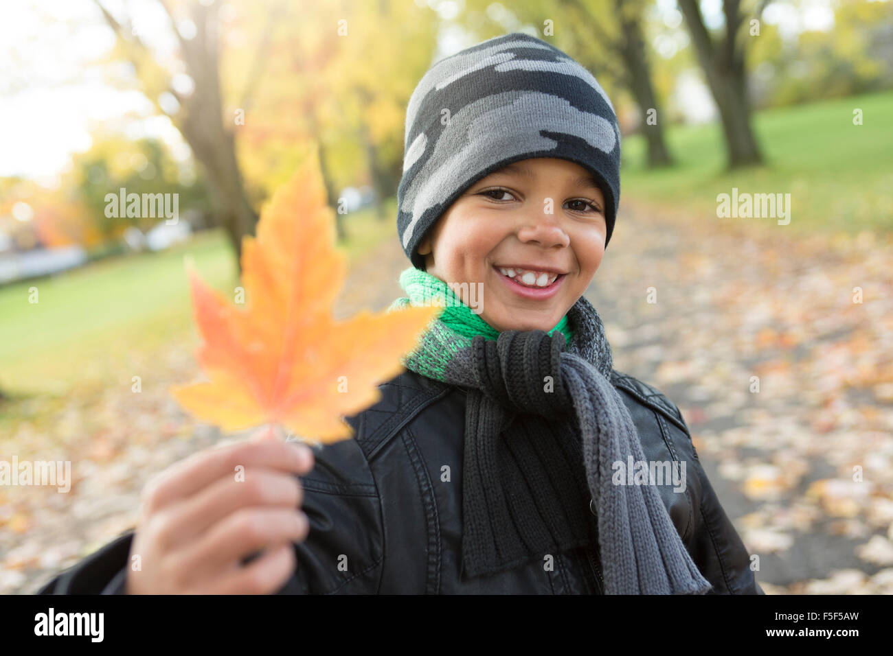 süsser Boy mit Herbstlaub im park Stockfoto