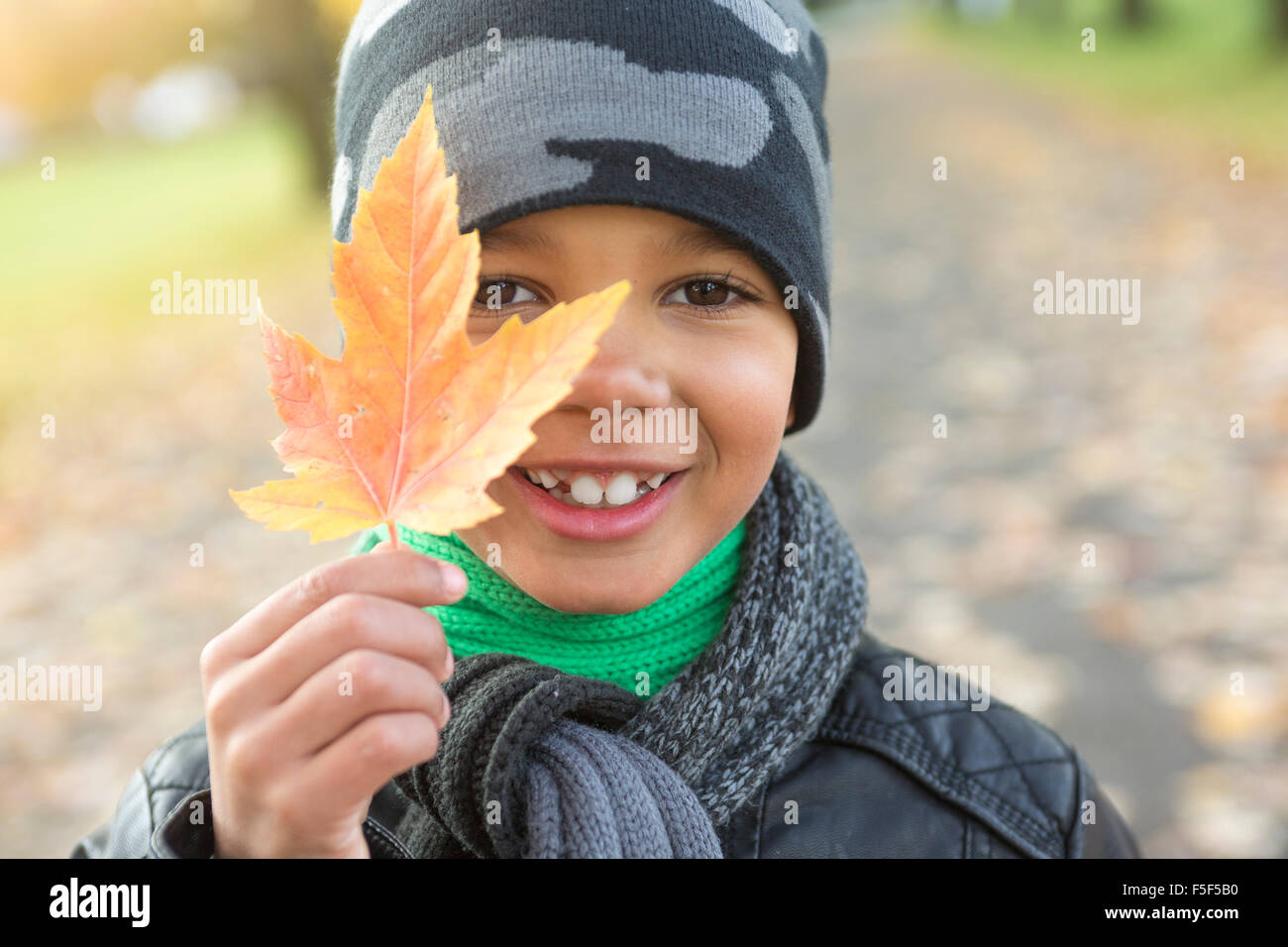 süsser Boy mit Herbstlaub im park Stockfoto