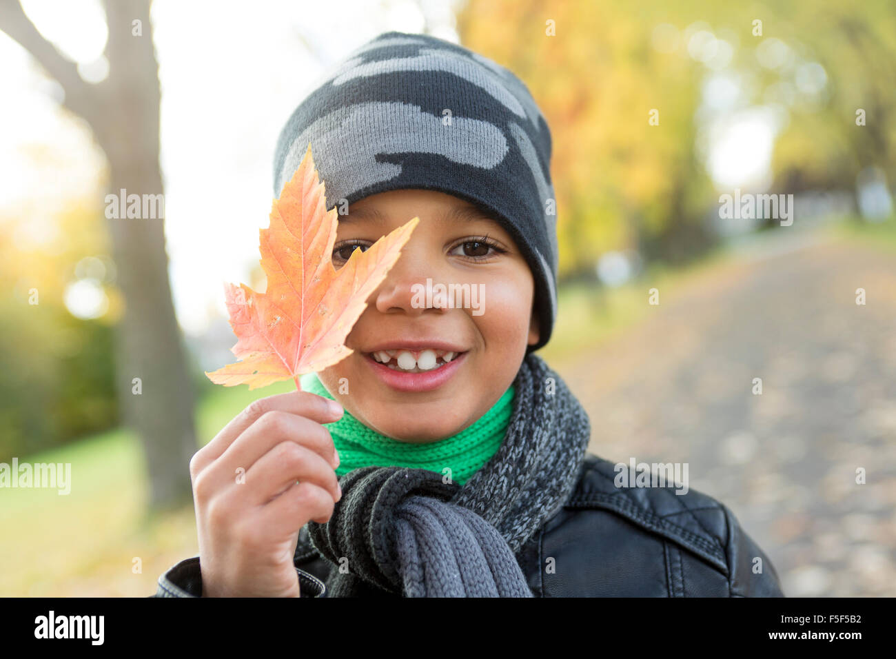 süsser Boy mit Herbstlaub im park Stockfoto