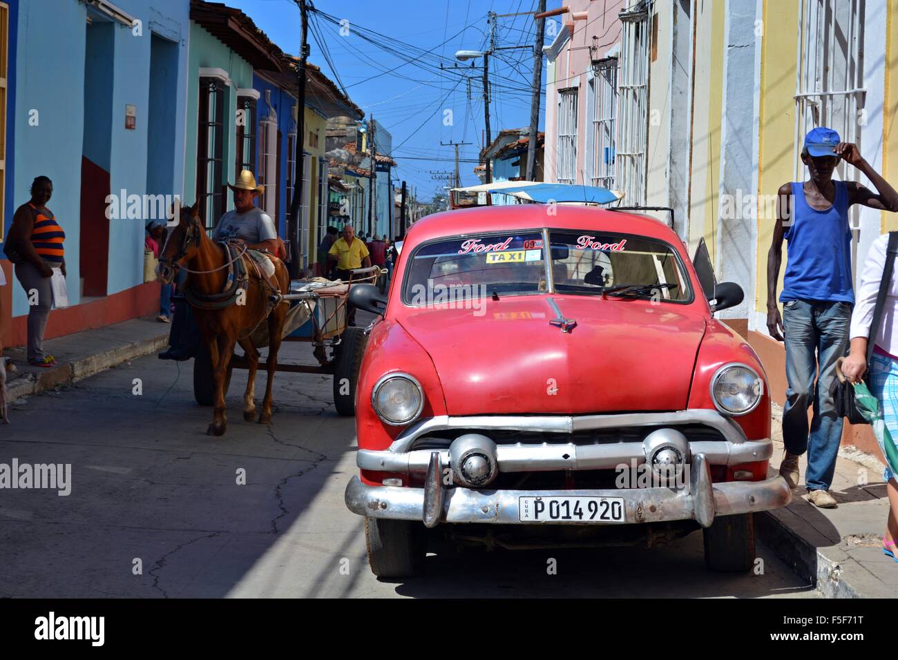 Alten roten Ford-Taxi Parken in der Sonne auf einer bunten Straße in Trinidad Kuba mit Pferd und Wagen und Einheimischen zu Fuß durch Stockfoto