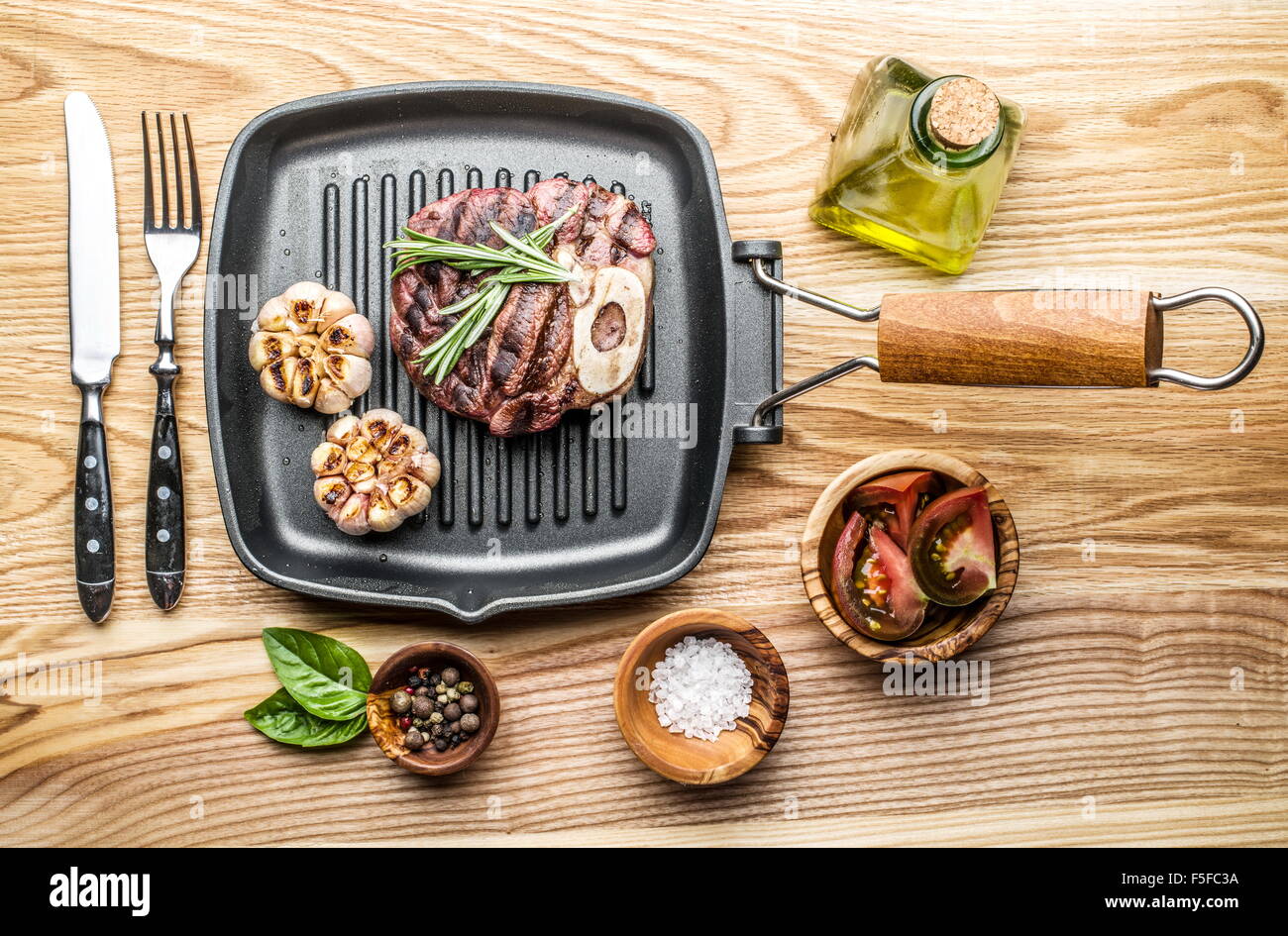 Rindersteak mit Gewürzen auf Pfanne auf Holztisch. Stockfoto