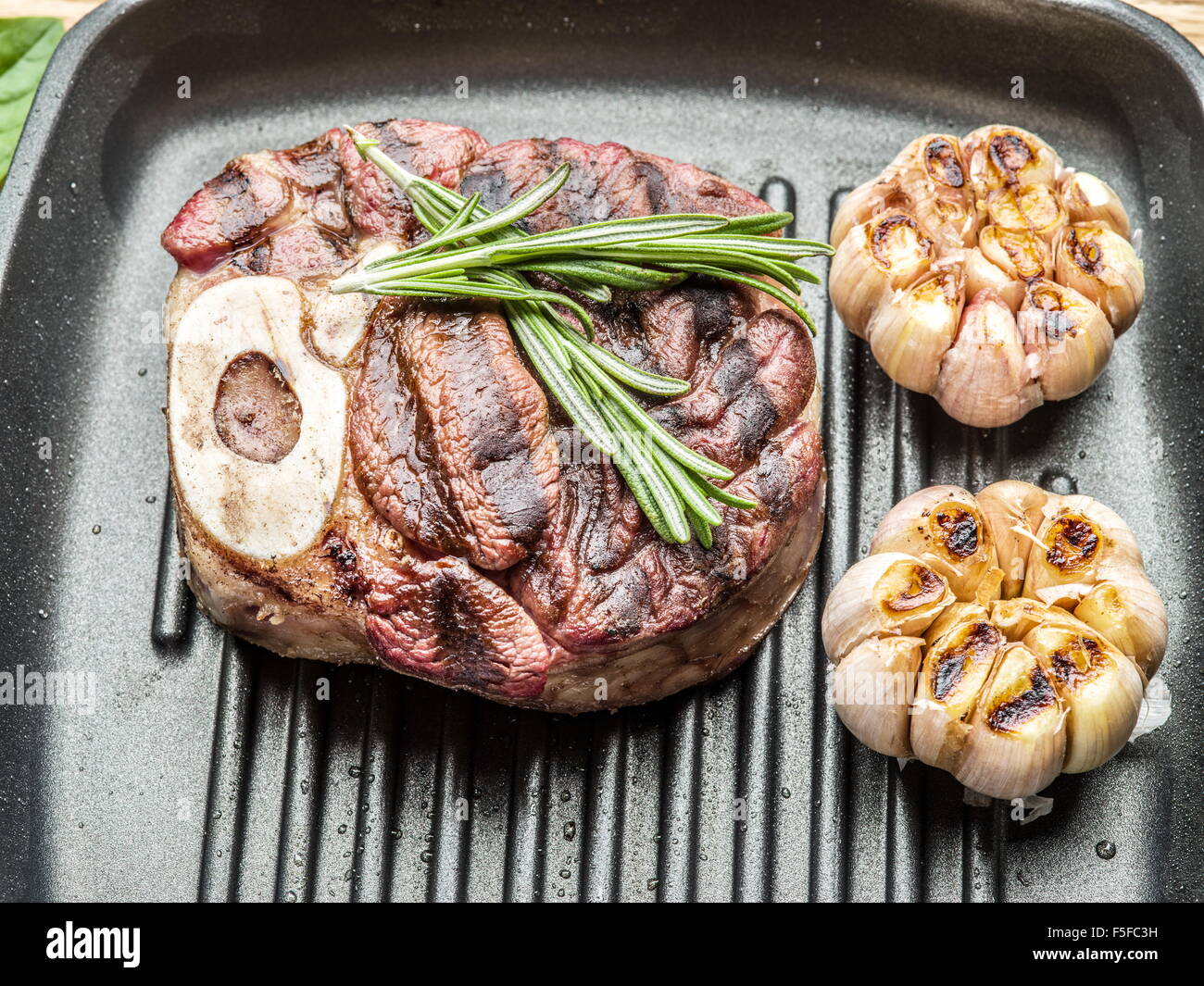 Rindersteak mit Gewürzen auf Pfanne auf Holztisch. Stockfoto
