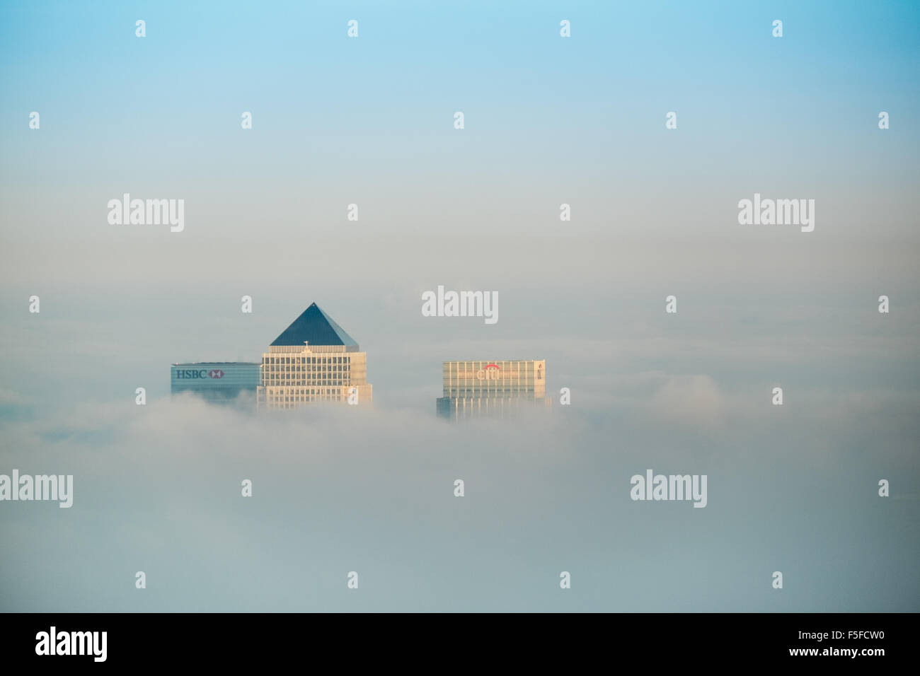 Die Dächer von Hochhäusern der Docklands vor Sonnenuntergang durch die steigenden Nebel und Wolken vor blauem Himmel ragt. Stockfoto
