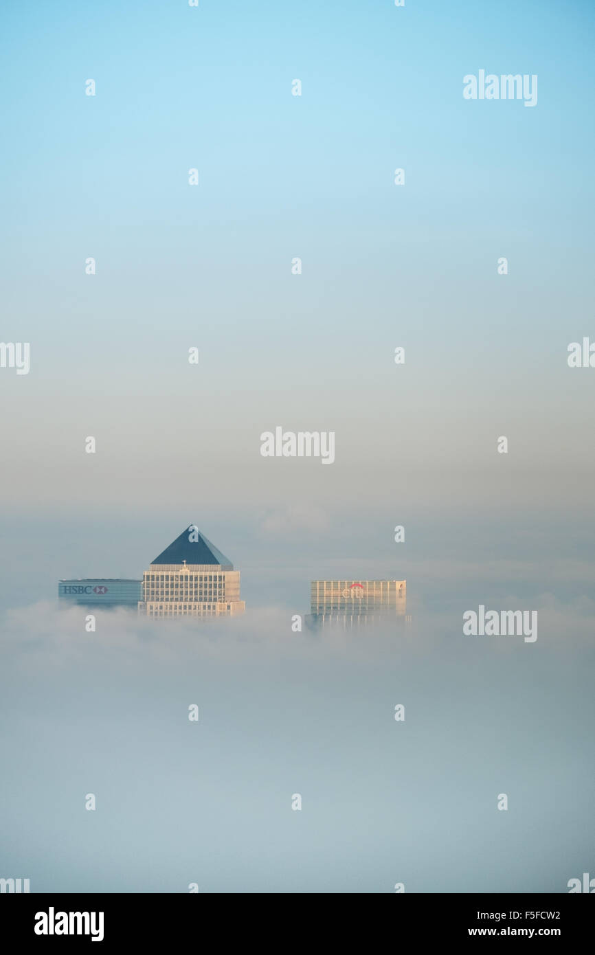Die Dächer von Hochhäusern der Docklands vor Sonnenuntergang durch die steigenden Nebel und Wolken vor blauem Himmel ragt. Stockfoto