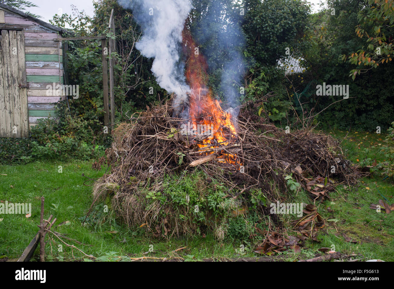 Eine herbstliche Lagerfeuer brennt die holzigen Gartenabfälle aus einer klaren Stockfoto