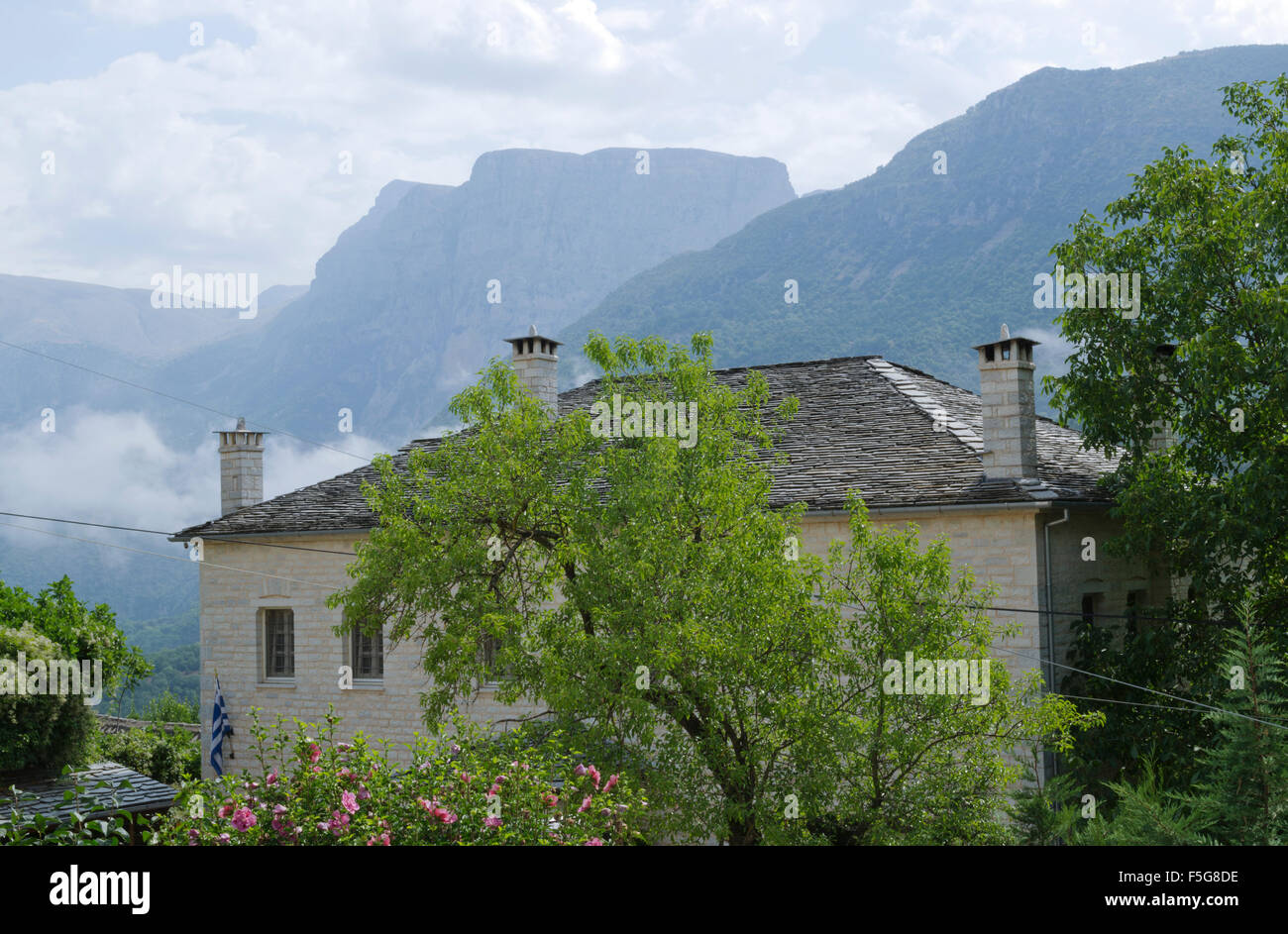 Haus in einem kleinen Dorf im Norden von Griechenland eingebettet im grünen und mit den Bergen im Hintergrund. Stockfoto