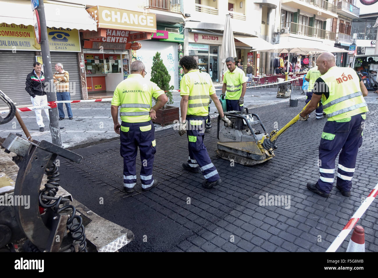 Spanischen Arbeiter bereiten eine künstliche Pflasterdecke Oberfläche mithilfe eines Rasters in weichen Asphalt gezwungen Stockfoto