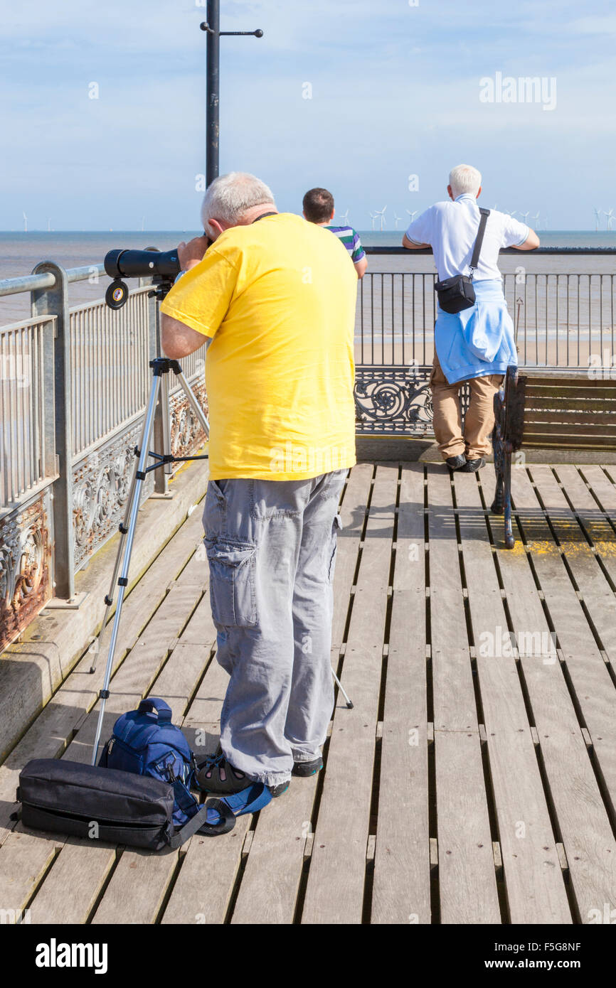 Mann durch ein Teleskop oder Umfang anzeigen das Meer oder den Strand vom Ende der Pier in Skegness, Lincolnshire, England, Vereinigtes Königreich, Stockfoto