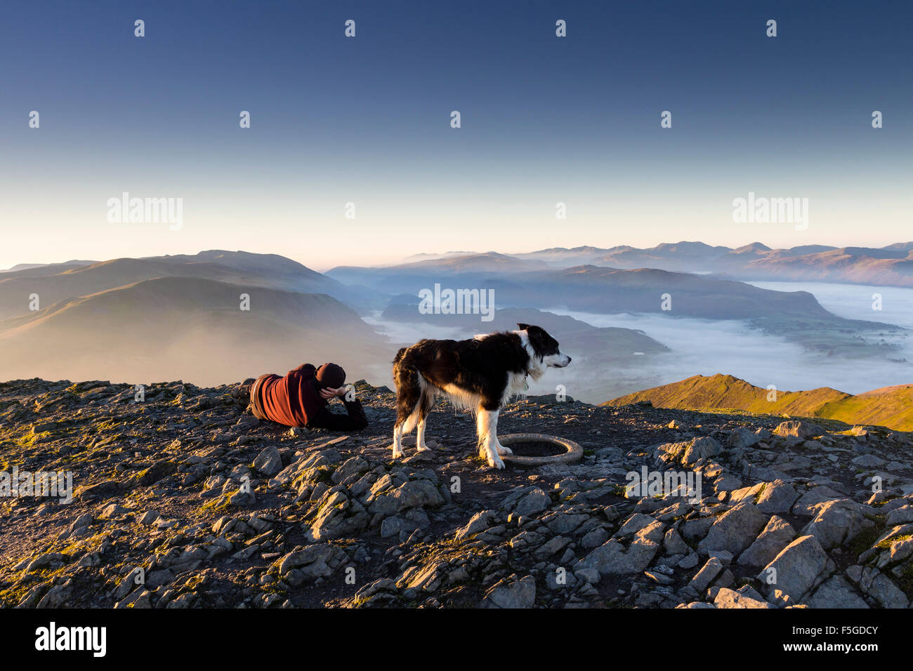 Ein Mann und sein Hund entspannend auf dem Gipfel des Blencathra Seenplatte Cumbria UK Stockfoto